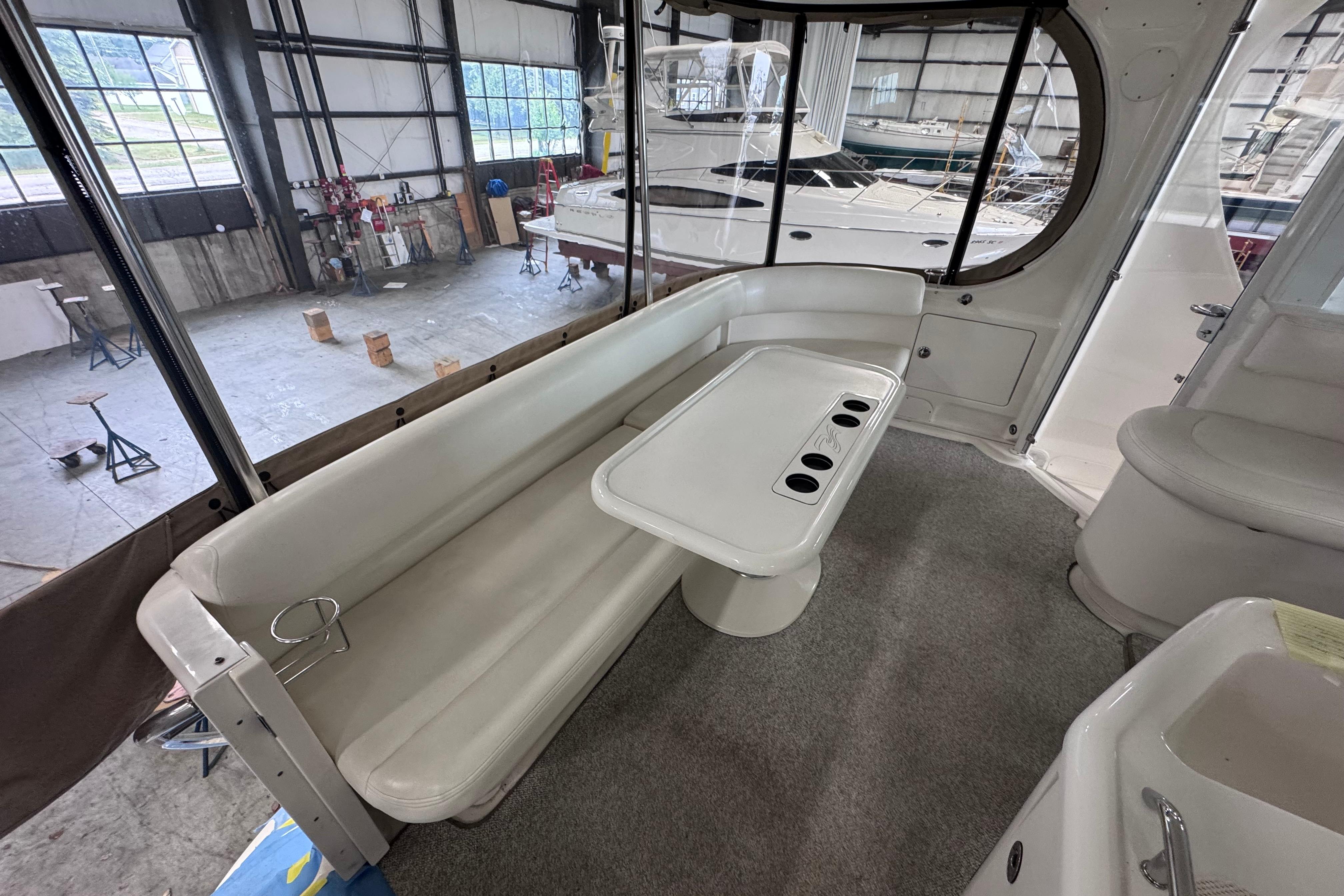 2004 Sea Ray 390 Motor Yacht interior with white seating and table in a spacious cabin.