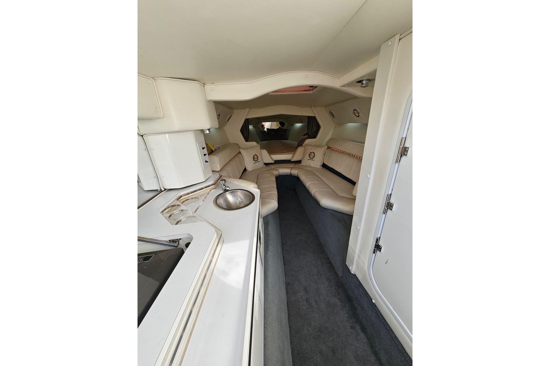 Luxurious interior of a 2004 Fountain 42 Lightning boat with plush seating and kitchenette.
