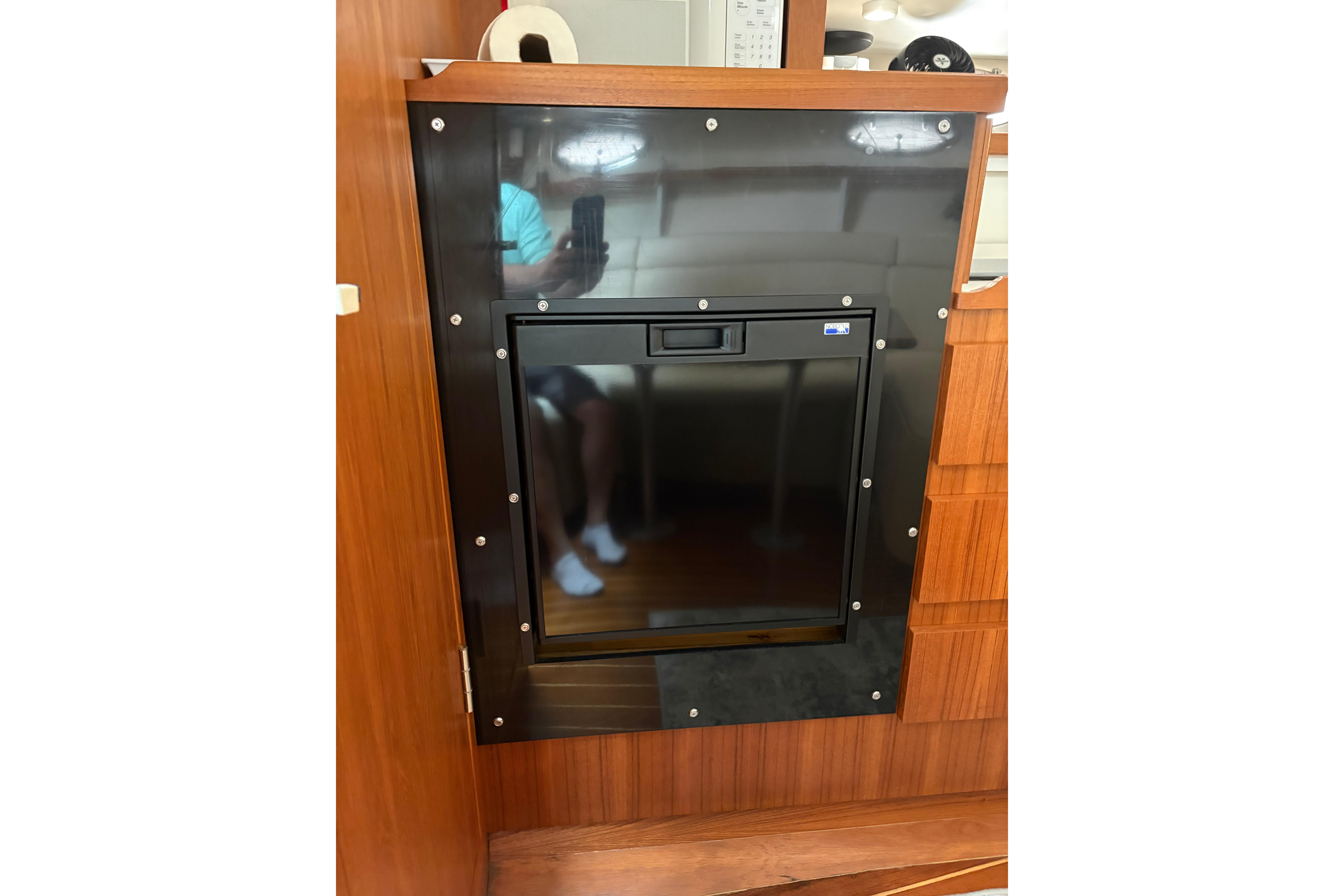 Built-in refrigerator on a 1999 Tiara Yachts 3100 Open, featuring sleek wood paneling.