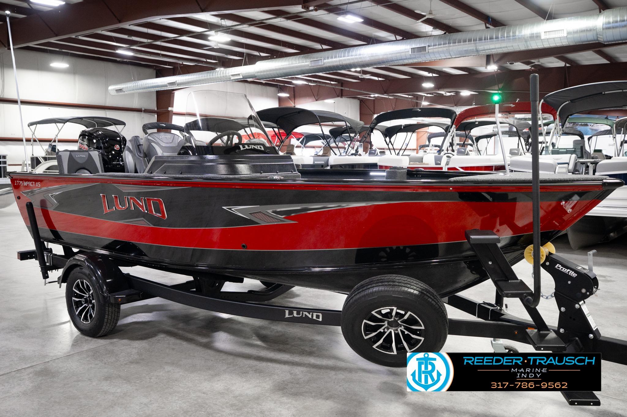 2026 Lund 1775 Impact XS SS boat in showroom, red and black design, on trailer.