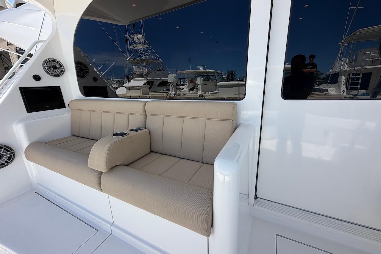 Luxurious seating area on a 2012 Viking 50 Convertible yacht, featuring beige cushions and cup holders.