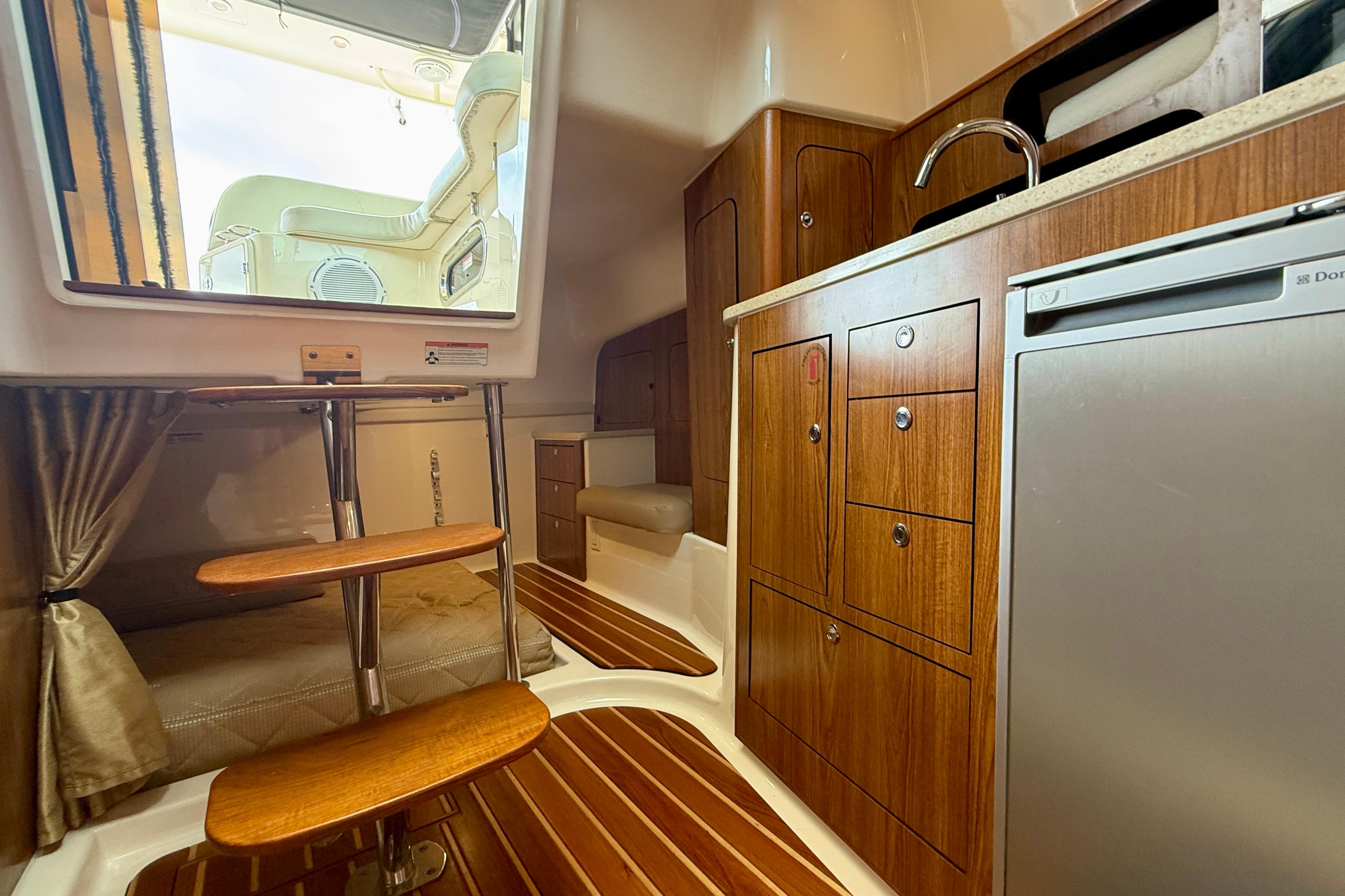 Interior of 2012 Pursuit OS 345 Offshore boat with wood cabinetry and compact kitchen area.