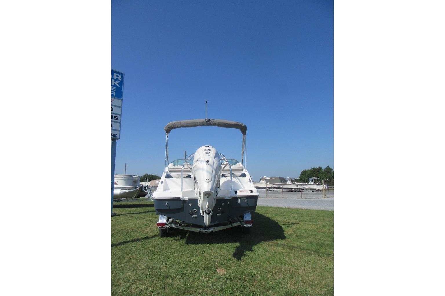 2027 Hurricane SunDeck 2486 OB boat on grass under clear blue sky.