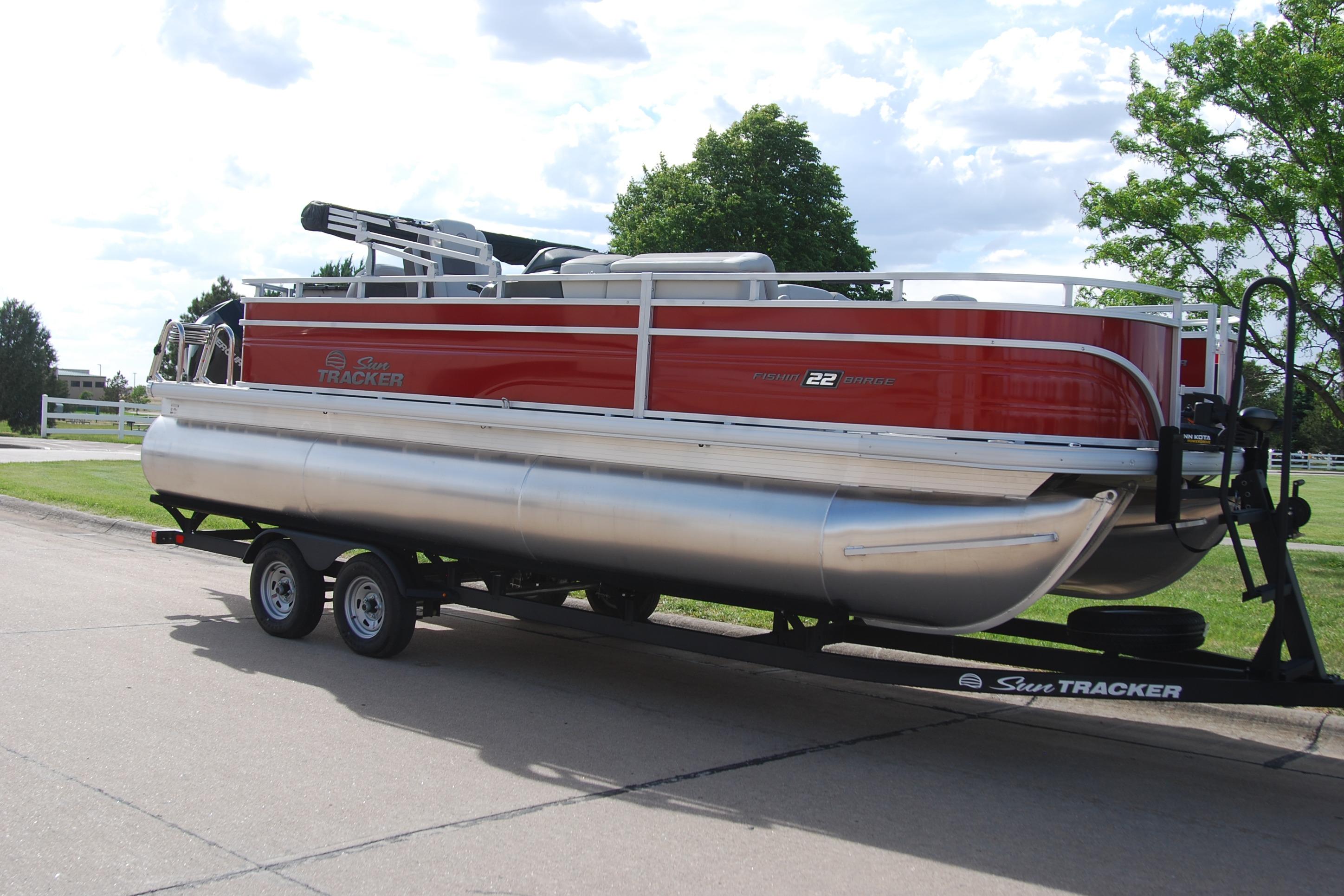 2026 Sun Tracker Fishin' Barge 22 XP3 pontoon boat on trailer, parked outdoors.