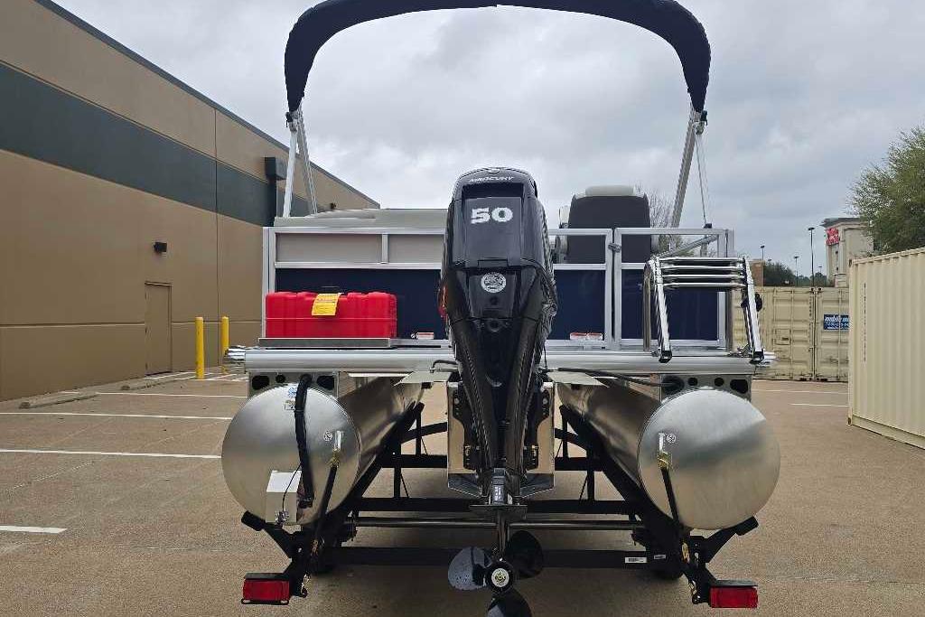 2026 Sun Tracker Bass Buggy 16 XL Select pontoon boat with outboard motor in parking lot.