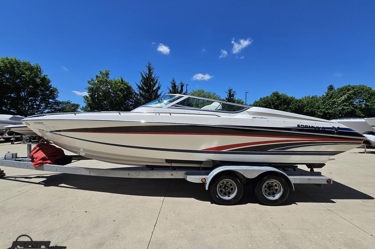 2005 Formula 271 FASTech boat on trailer under clear blue sky.