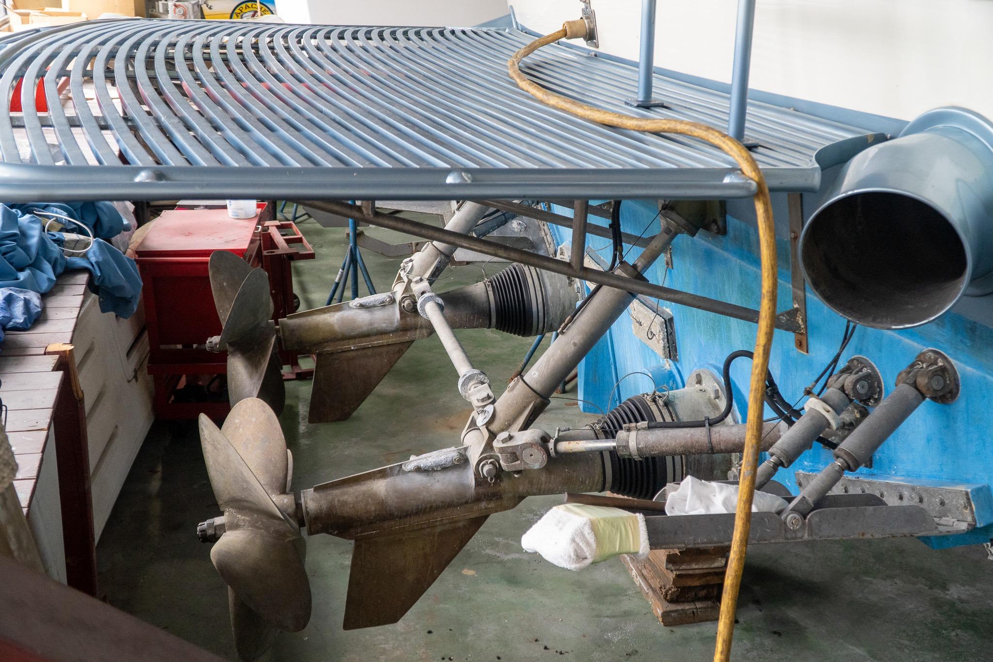 Boat propellers and drive system of a 1997 Magnum 56 model in a maintenance area.