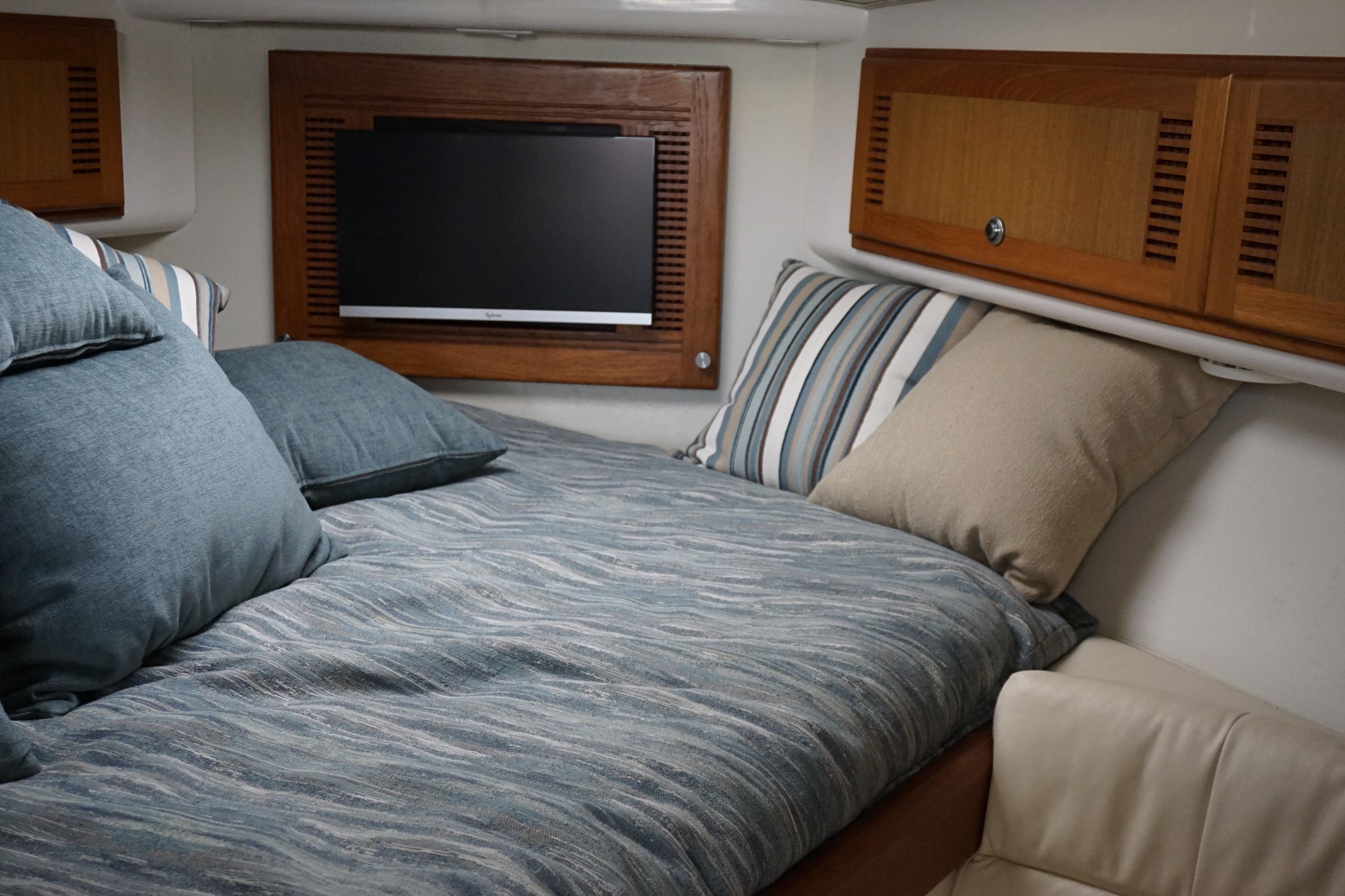 2005 Cabo 35 Express cabin interior with cozy bedding and wall-mounted TV.