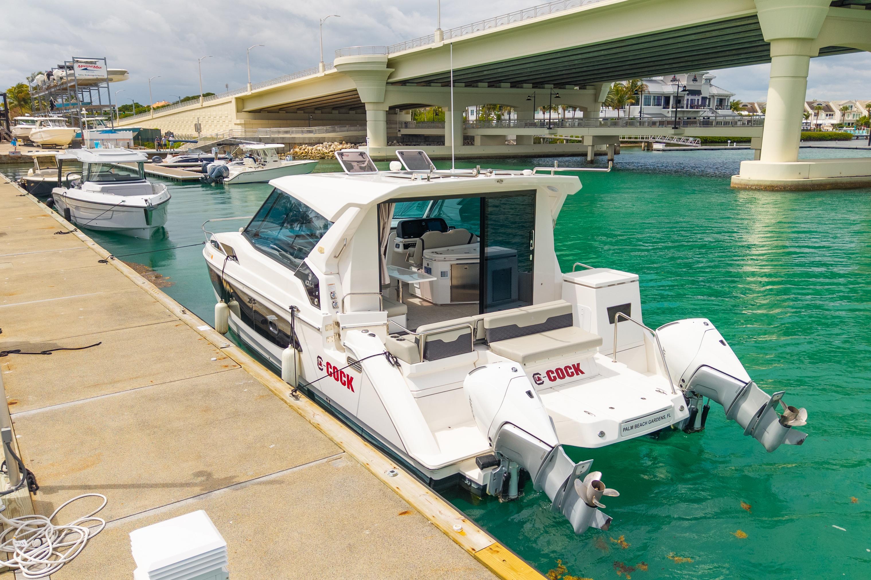2025 Aquila 36 Cruiser docked by a bridge in turquoise waters.