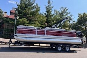 2026 Sun Tracker SportFish 22 DLX pontoon boat on trailer, parked outdoors.