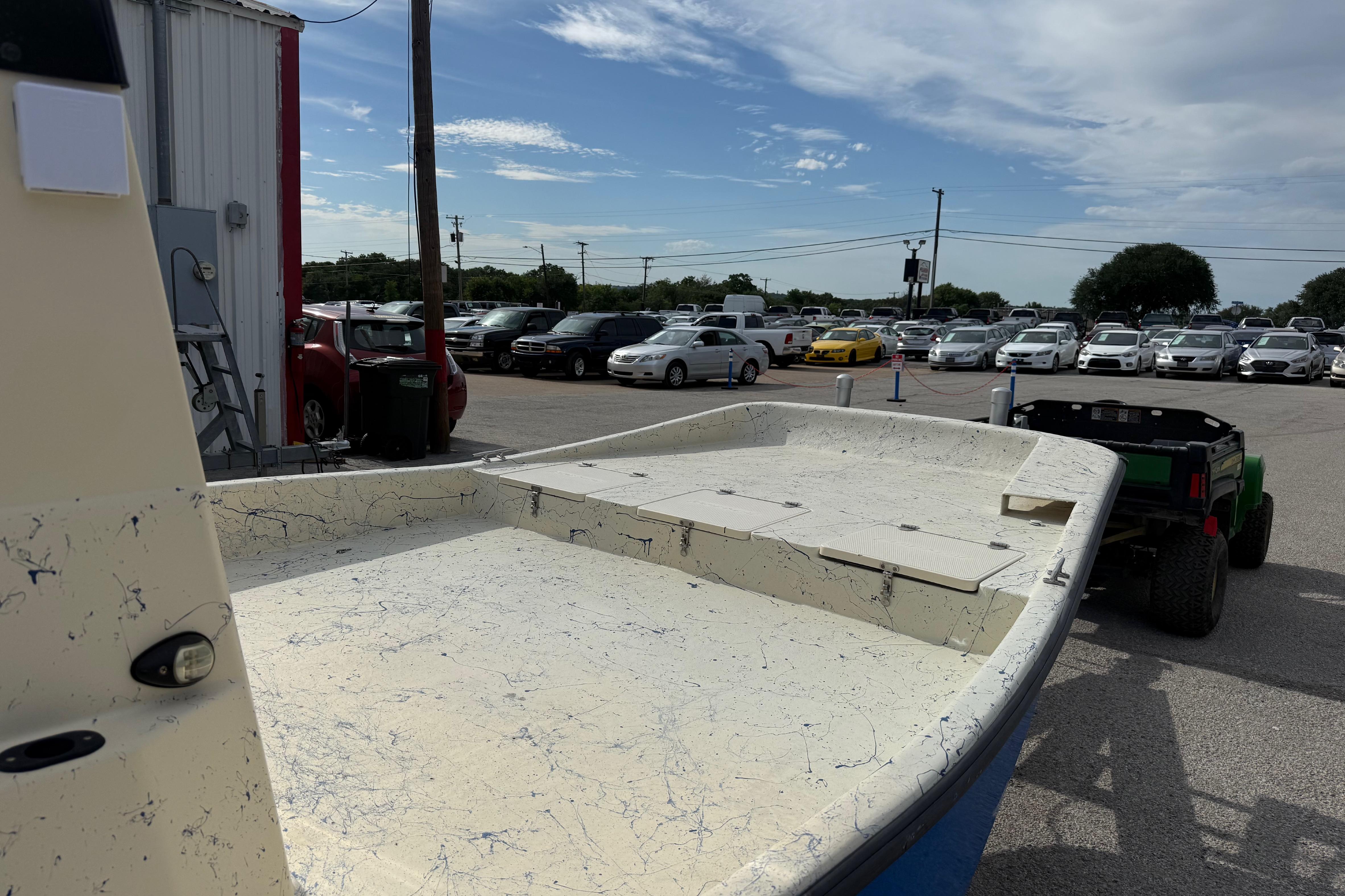 2007 Flats Cat 19 boat on trailer in parking lot with cars and cloudy sky.