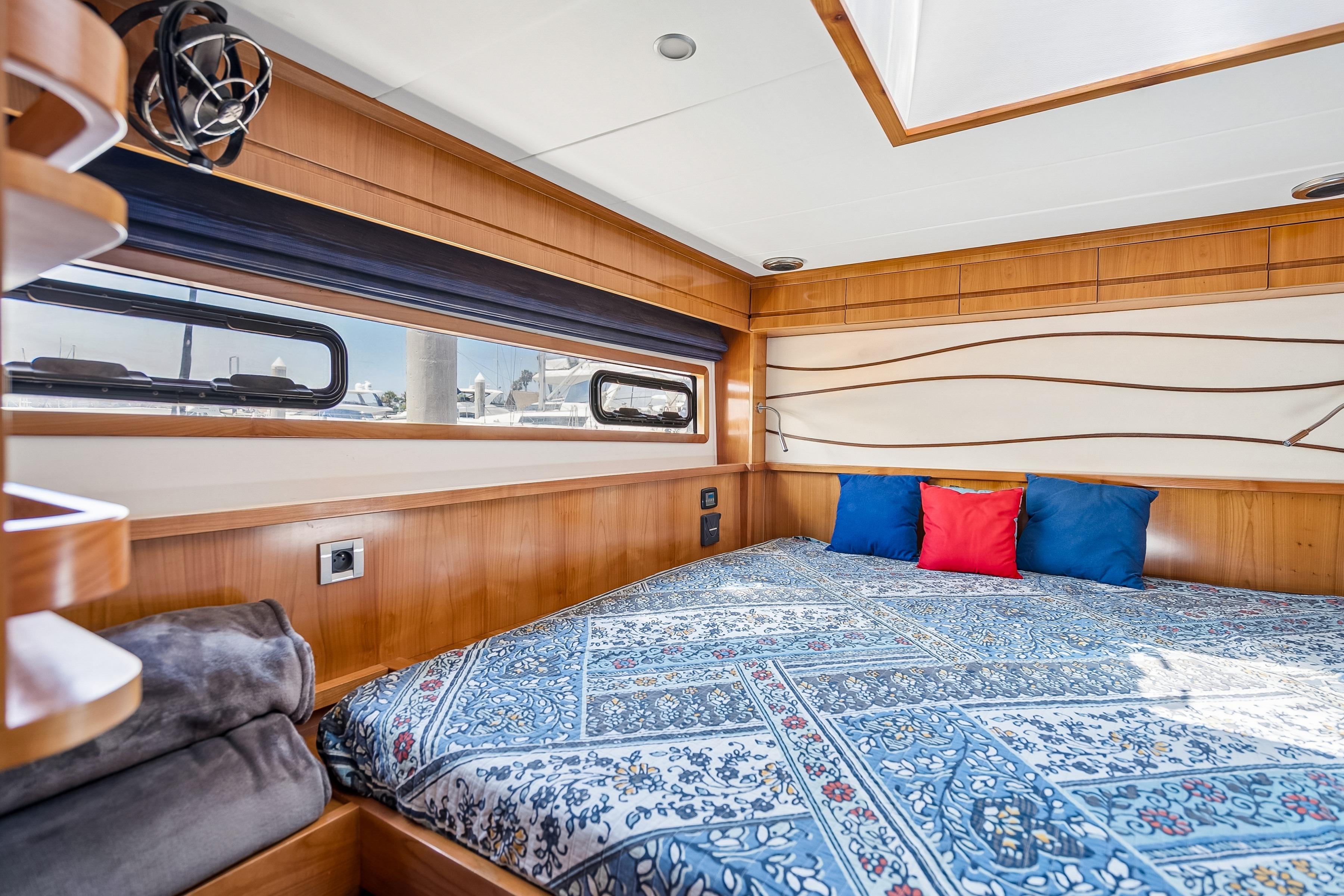 Luxurious 2009 Catana 65 yacht cabin with elegant wood finish and patterned bedding.
