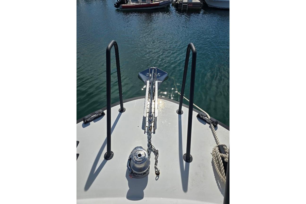Bow of 2022 Targa 37 boat with anchor and railing in marina.