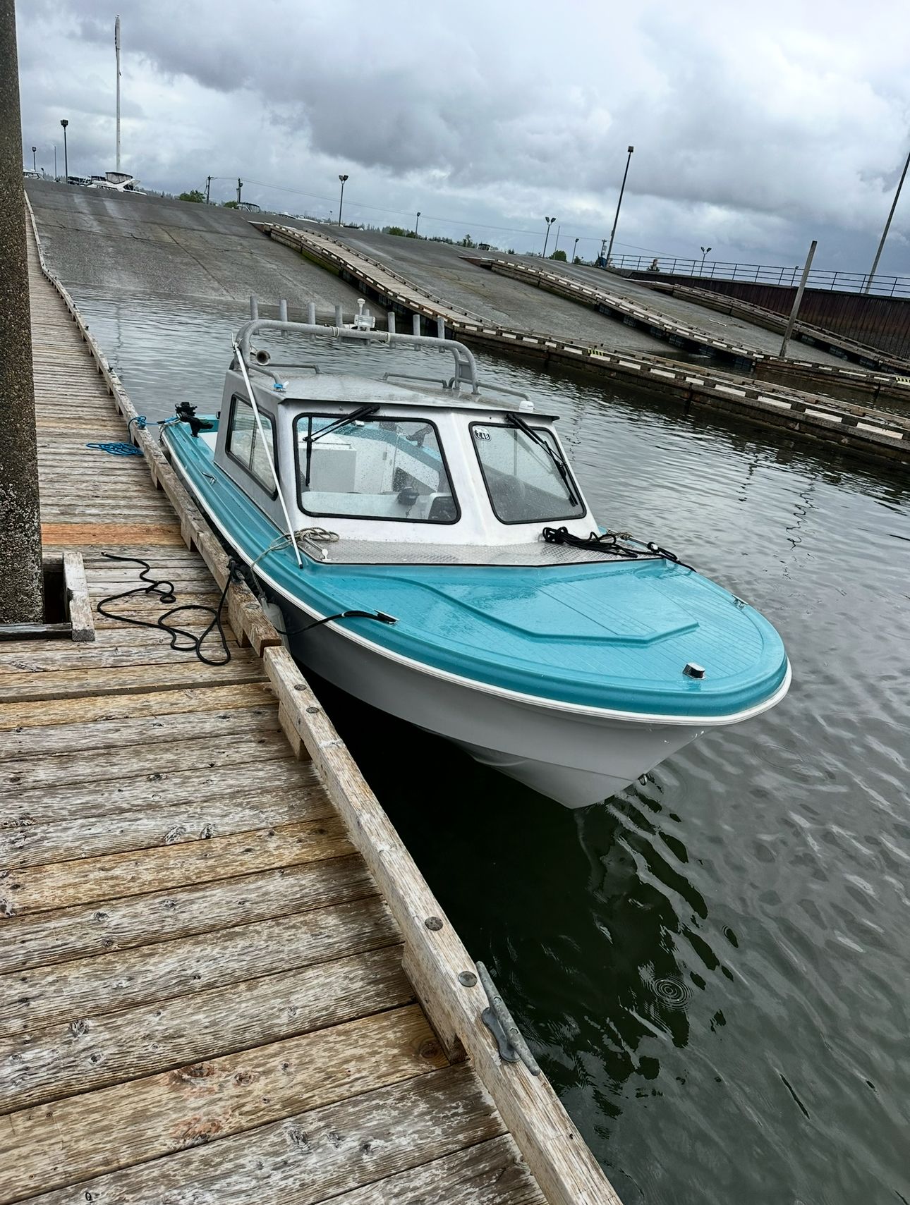 A restored 1967 Fiberform boat is docked at a wooden pier. It features a turquoise top.