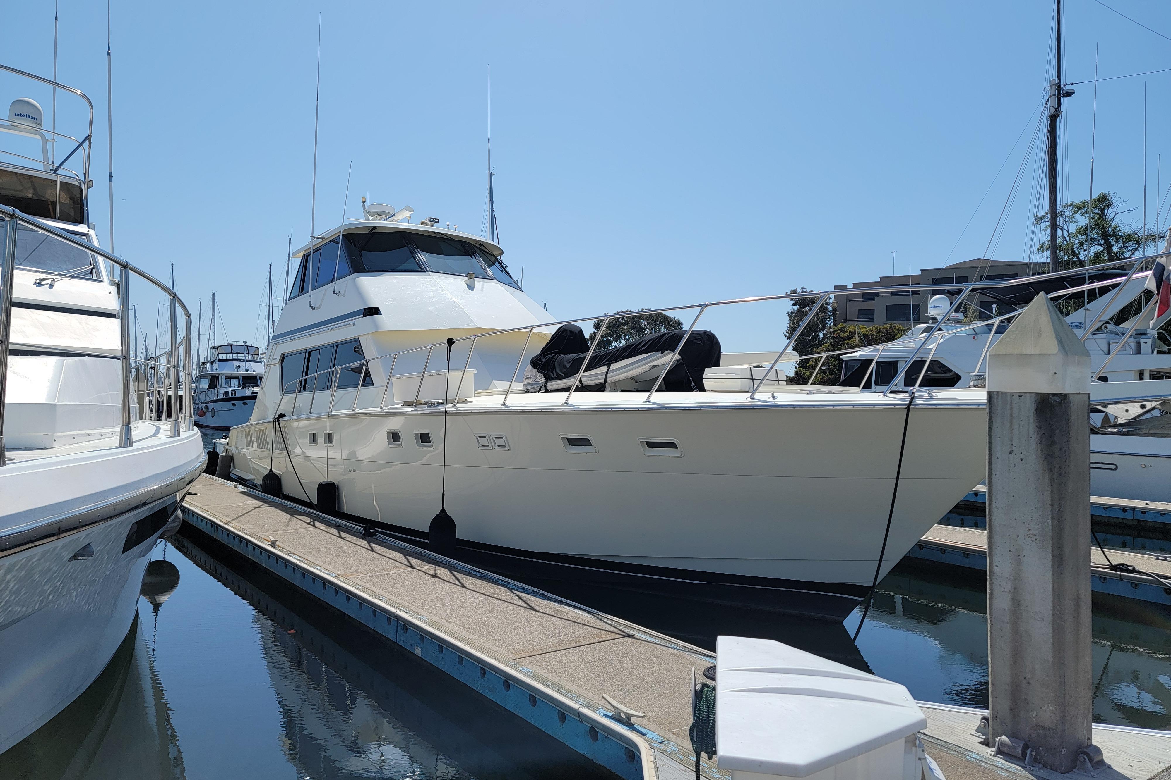 1989 Hatteras Convertible yacht docked at marina under clear blue sky.
