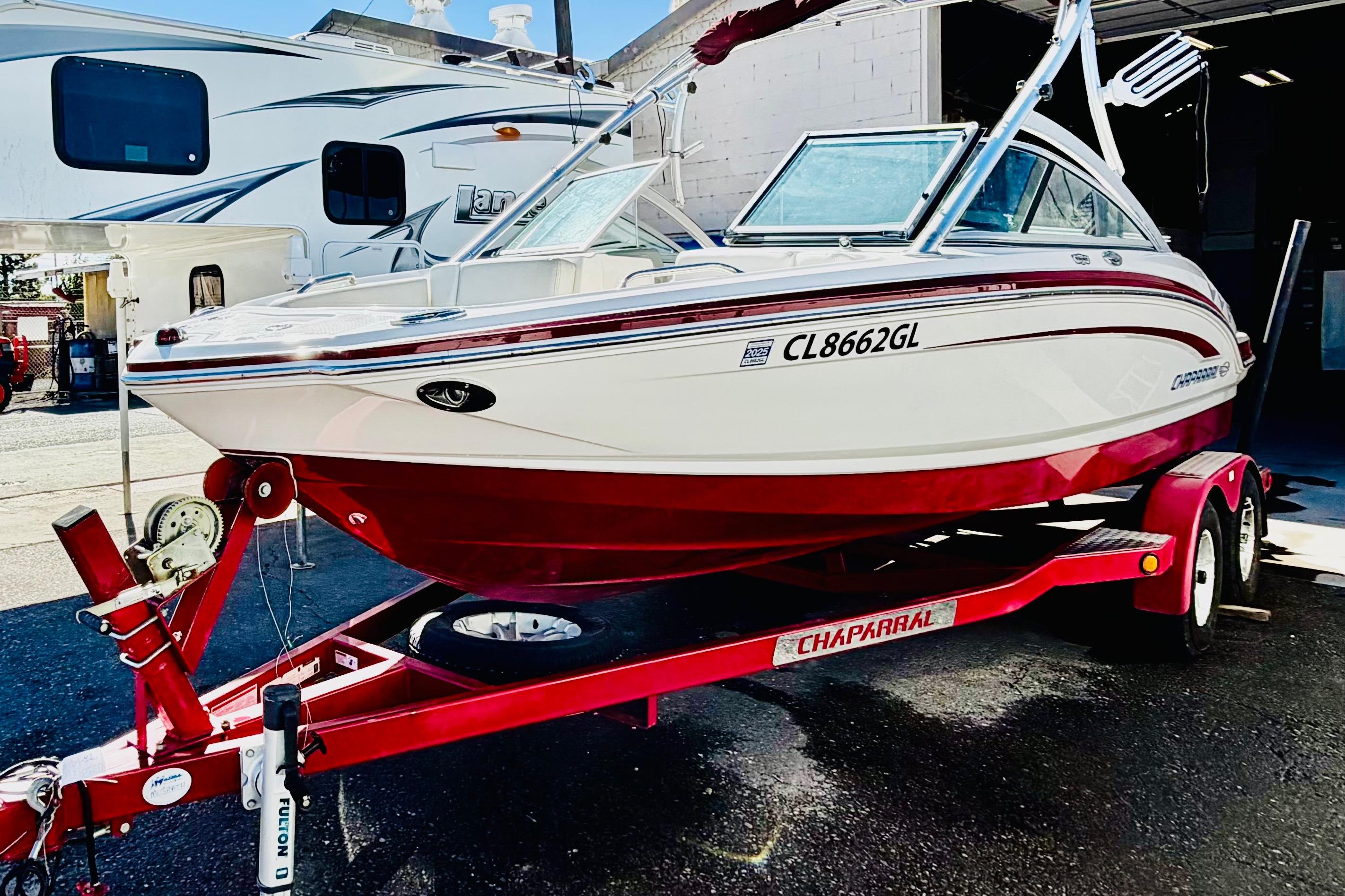 2013 Chaparral 206 SSi boat on red trailer, parked outdoors.
