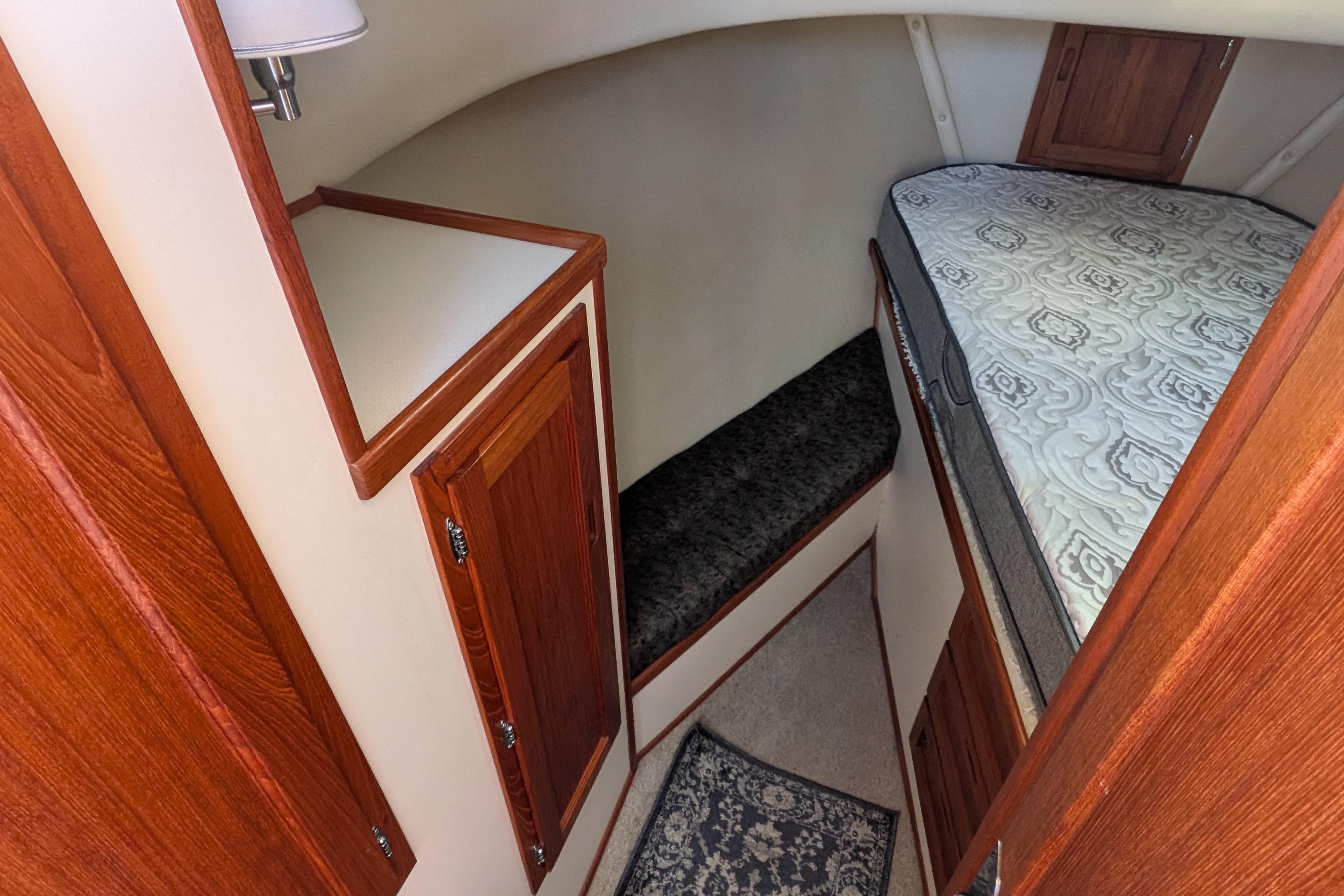 Cozy cabin interior of a 1998 Nordic Tug 32 with wood accents and patterned bedding.