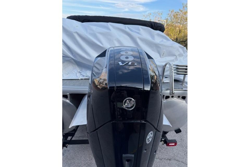 Outboard motor on 2026 Sun Tracker Fishin' Barge 22 XP3, covered and parked.