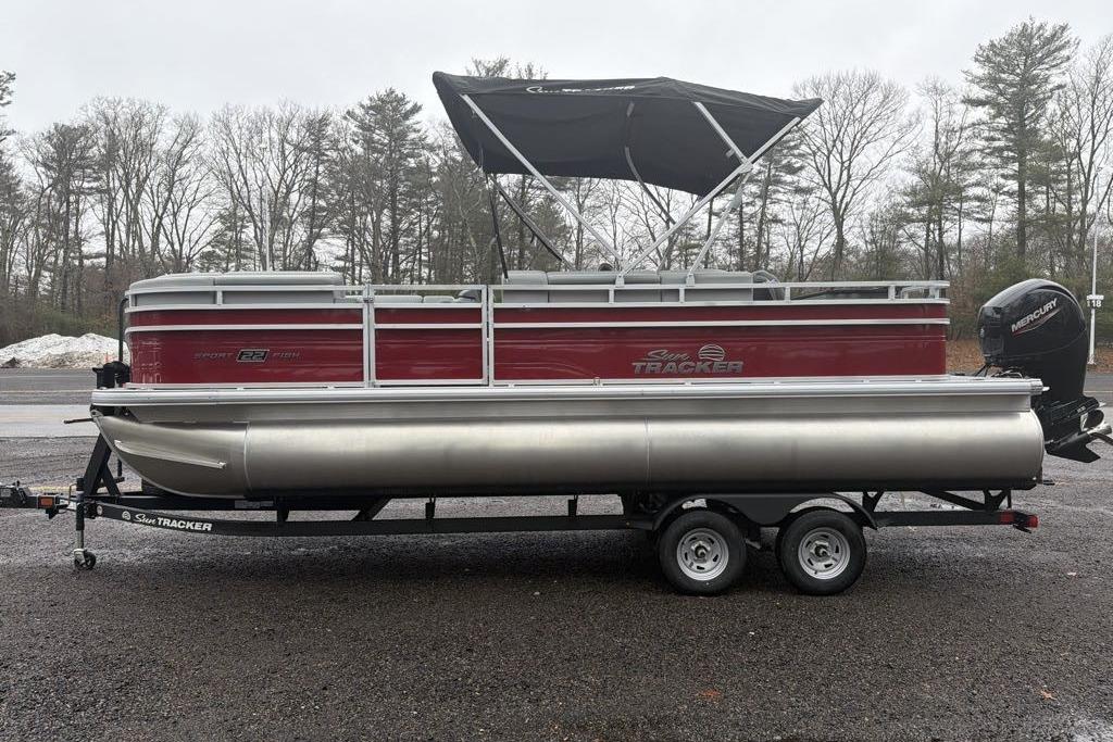 2026 Sun Tracker SportFish 22 DLX pontoon boat on trailer, parked outdoors.