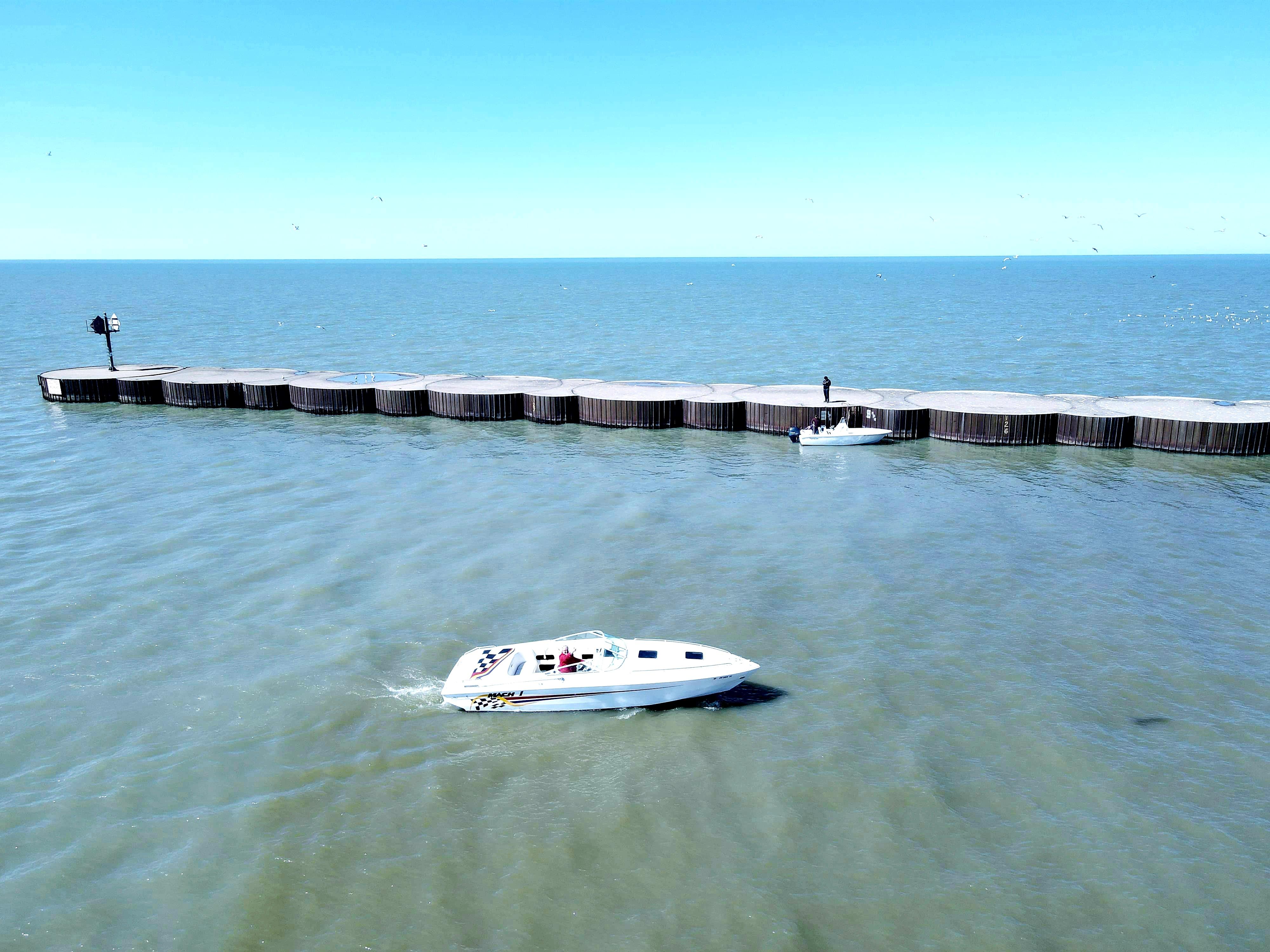 1999 Baha Cruisers 290 Mach 1 boat cruising near a breakwater on a sunny day.
