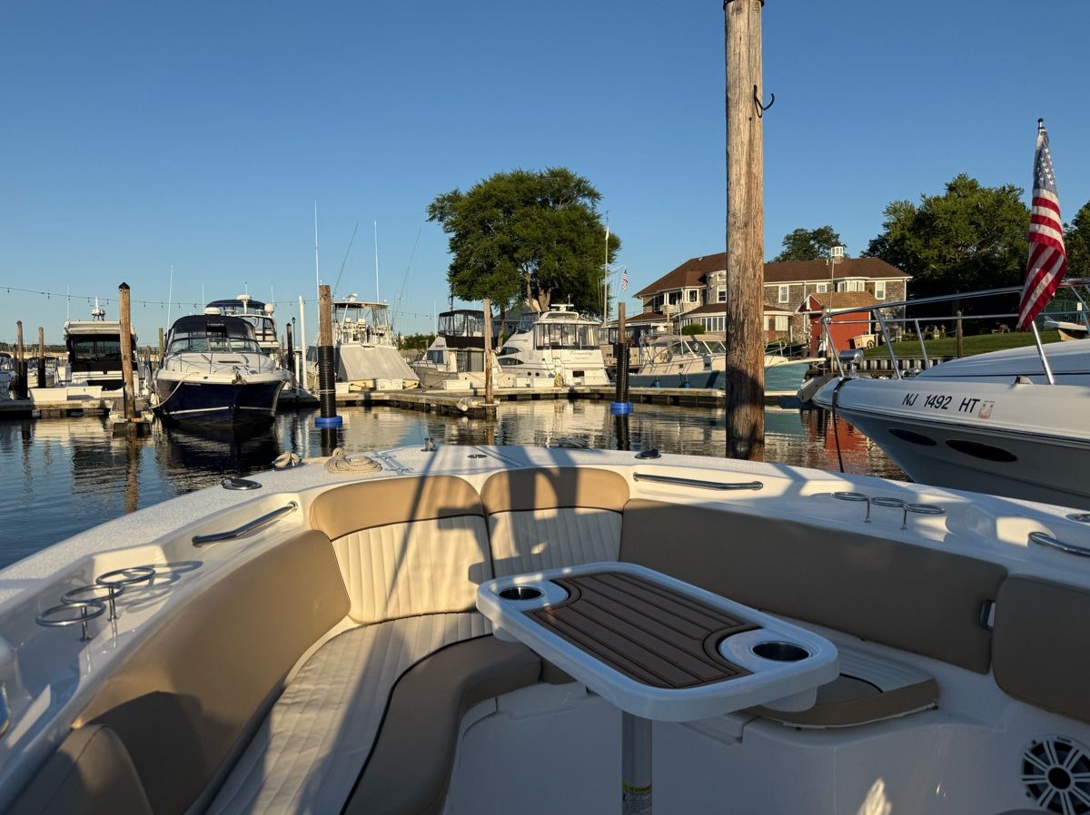 A 2017 Sea Fox Commander 266 docked in a marina. It features a cozy seating area with a table.
