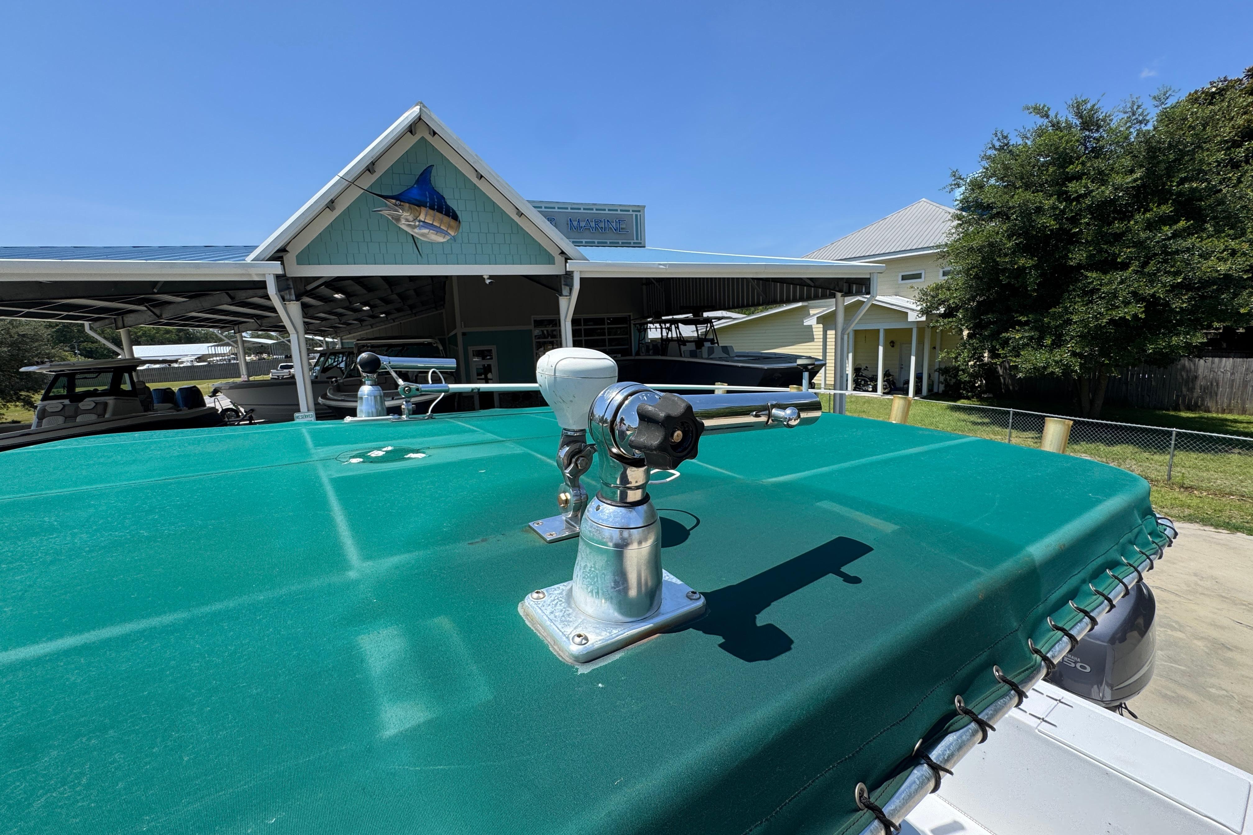 2000 Stamas 250 Tarpon boat with green cover, docked near a marina building.