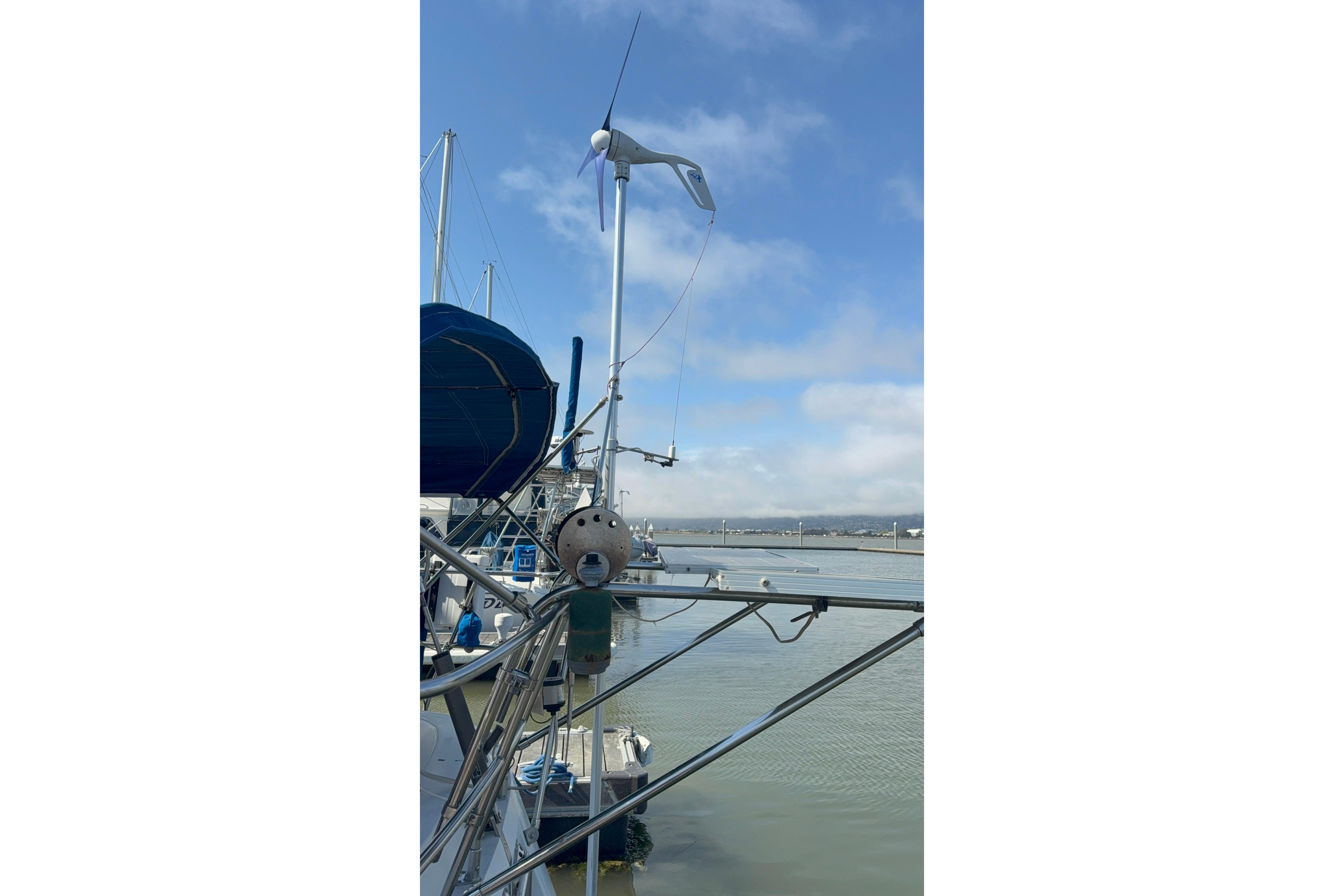 Sailboat Norseman 400, 1987 model, docked with wind turbine against blue sky.