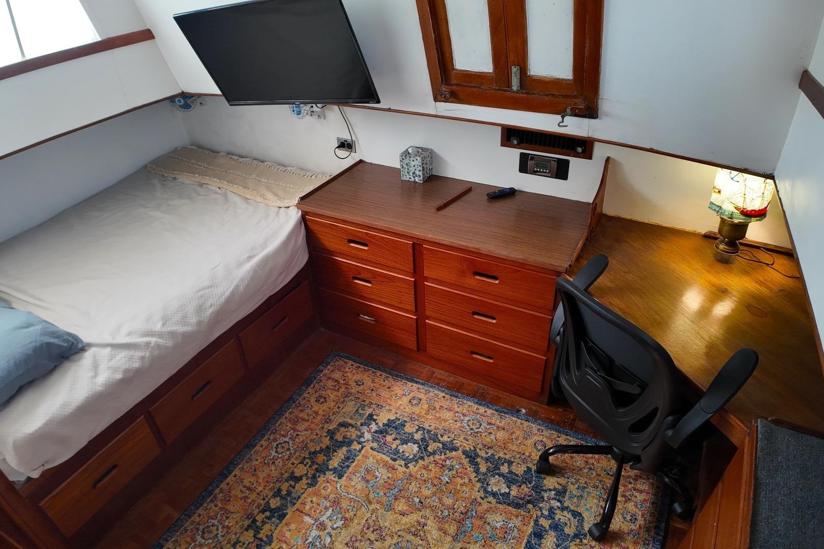 Cozy cabin interior of 1978 Grand Banks 42 Classic with bed, desk, and TV.