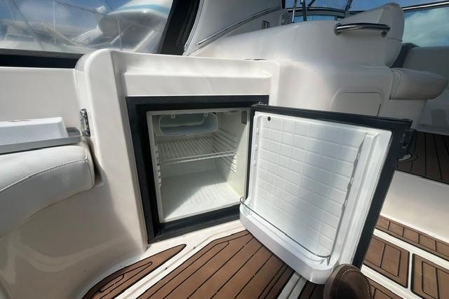 Open mini fridge on 2004 Cruisers Yachts 3372 Express, showcasing interior and deck flooring.