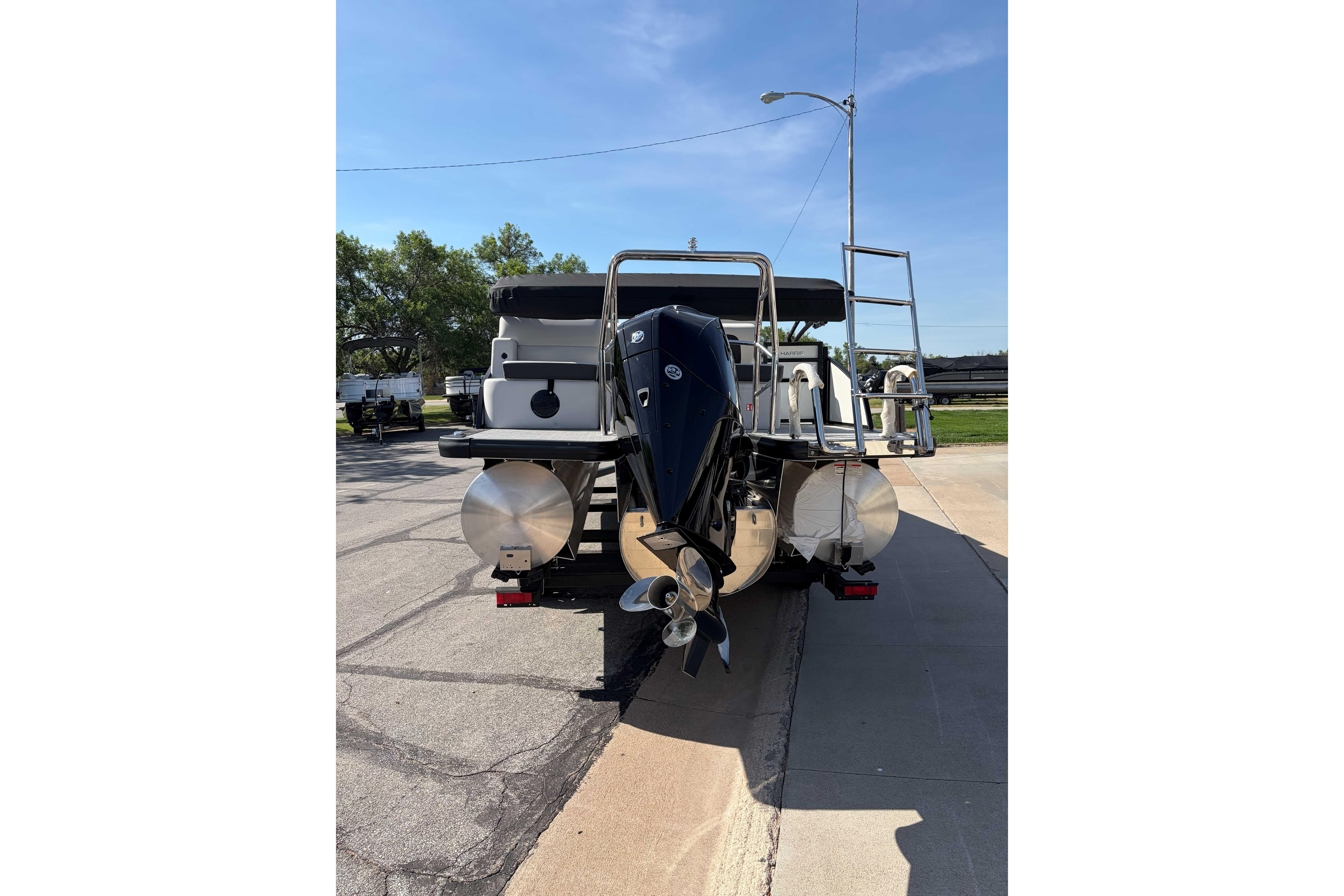 2025 Harris Cruiser 250 pontoon boat rear view with motor and ladder.