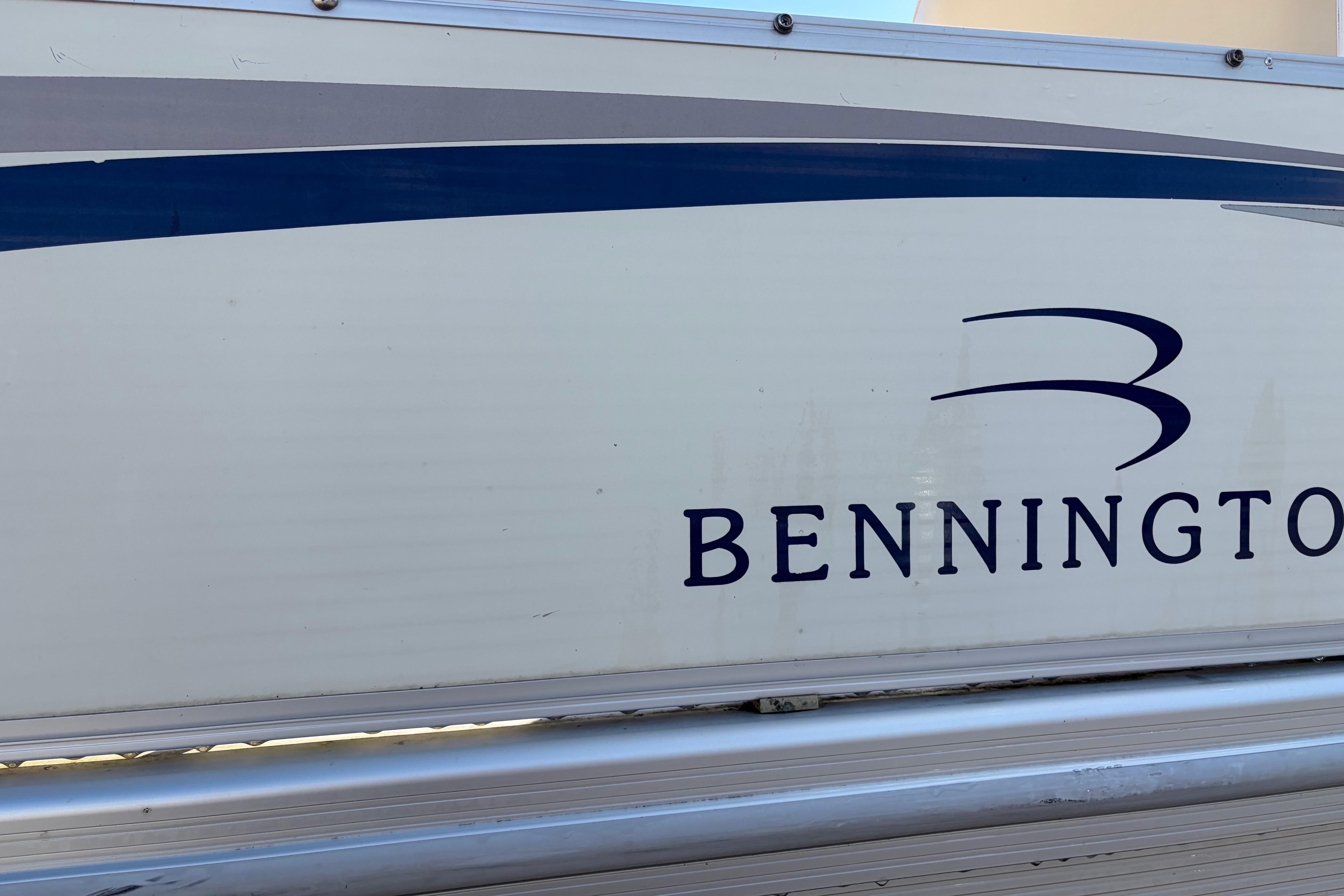 Side view of a 2003 Bennington 2250RSi boat with logo and blue stripe.