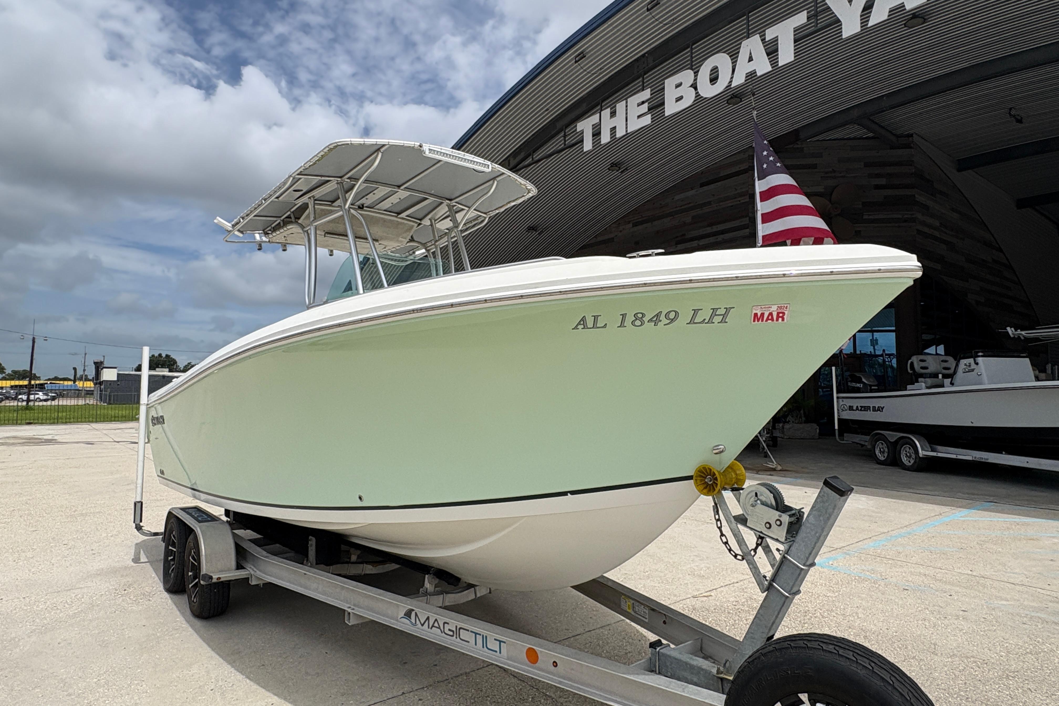 2006 Sail Faish 2360 boat on trailer at marina, American flag visible.