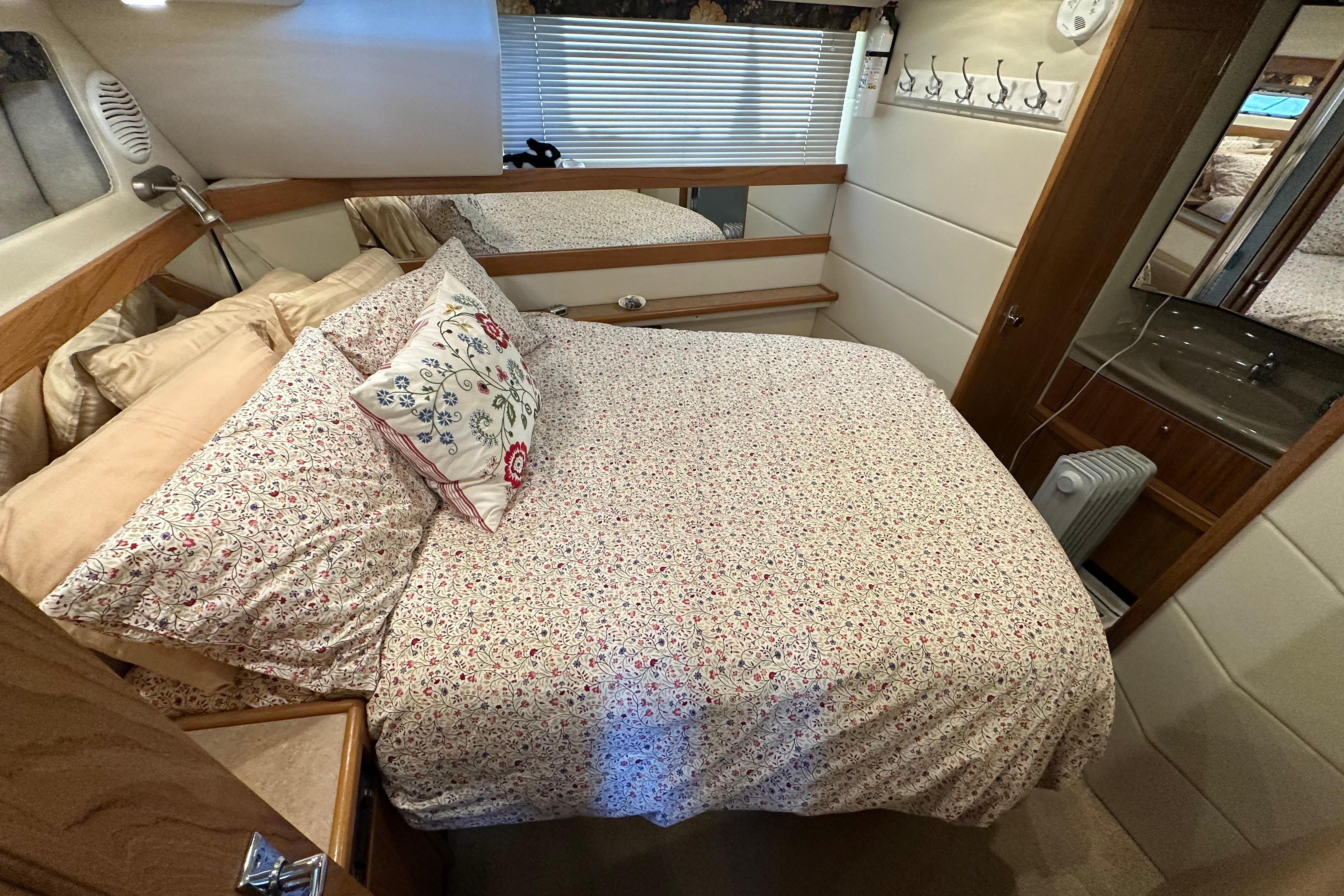Cozy bedroom in 2000 Bayliner 4087 Aft Cabin Motoryacht with floral bedding and wooden accents.