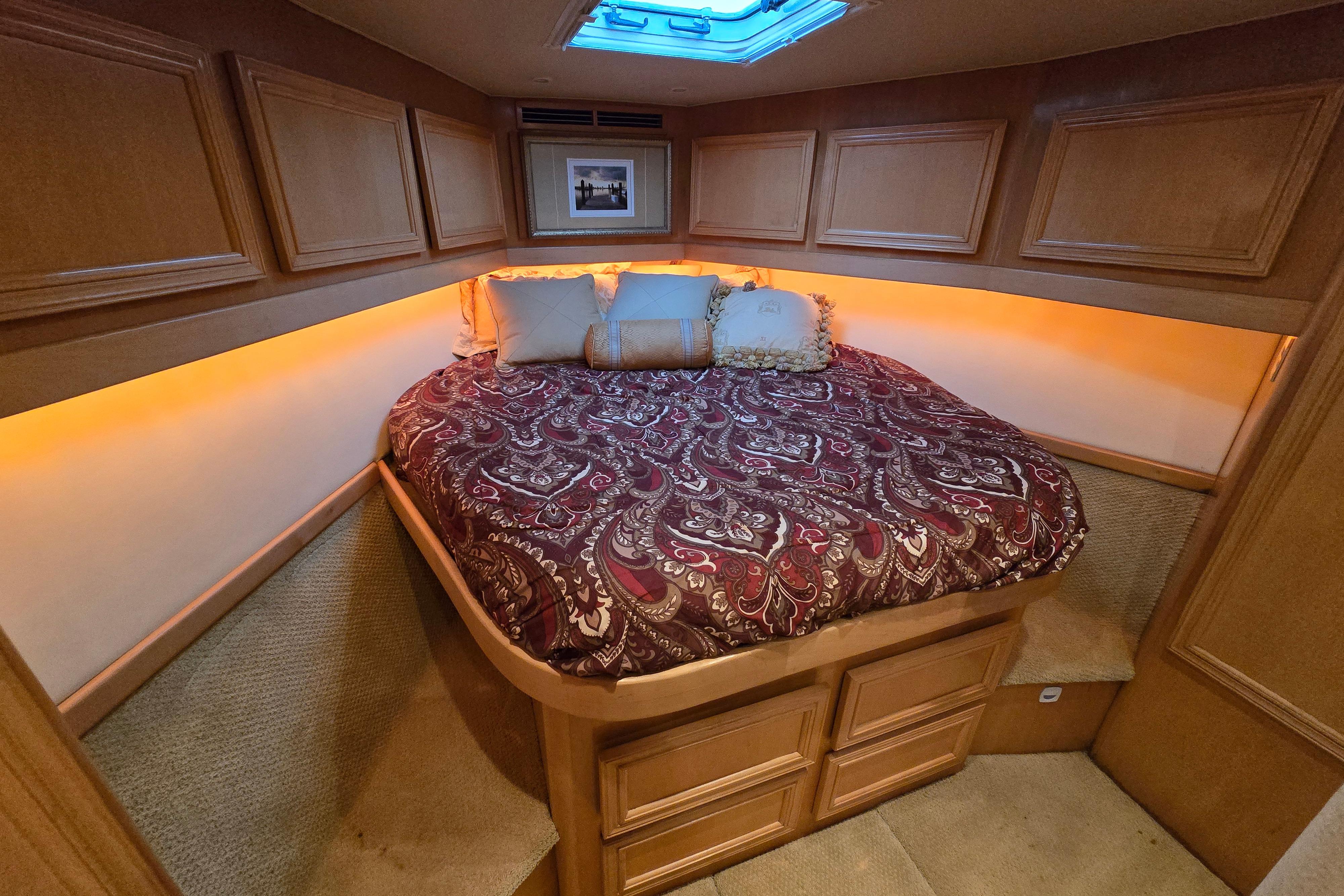 Luxurious cabin interior of 2001 Cavileer 53 Convertible yacht with cozy bed and ambient lighting.