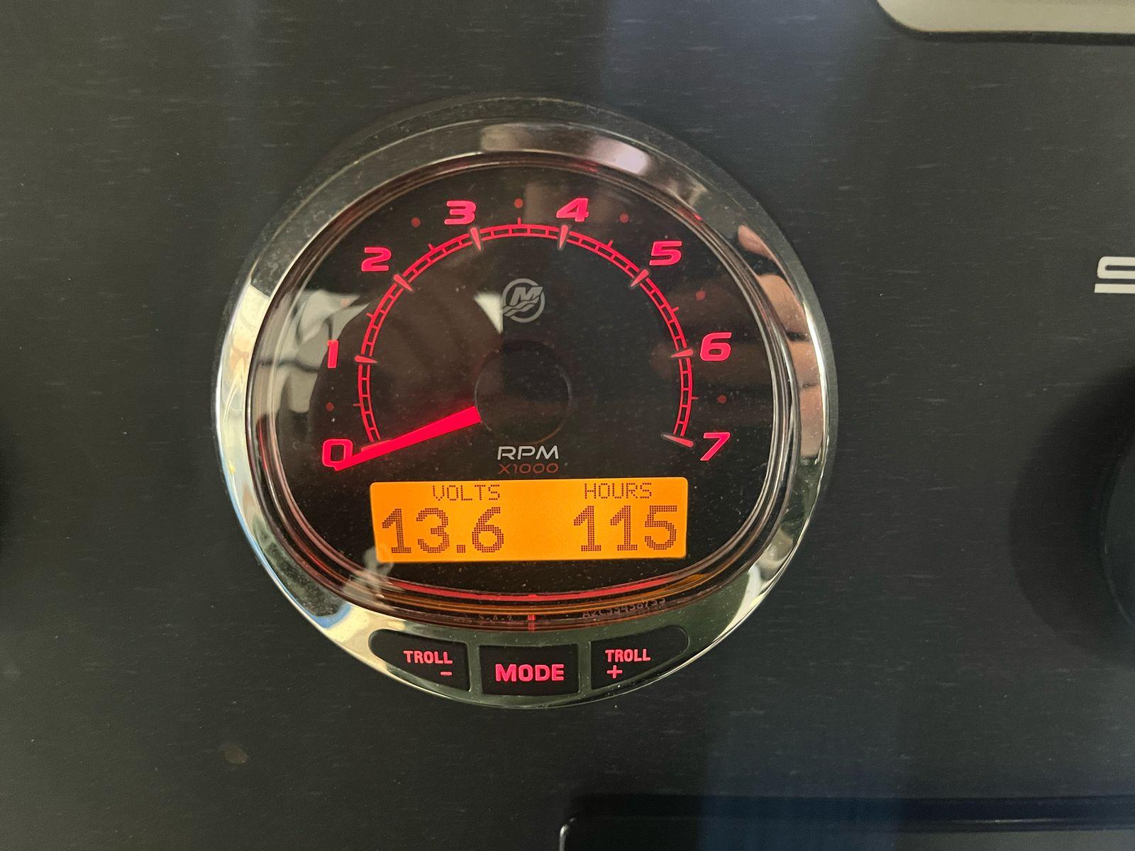 Close-up of a tachometer displaying 13.6 volts and 115 hours on a Scanner Envy 860.