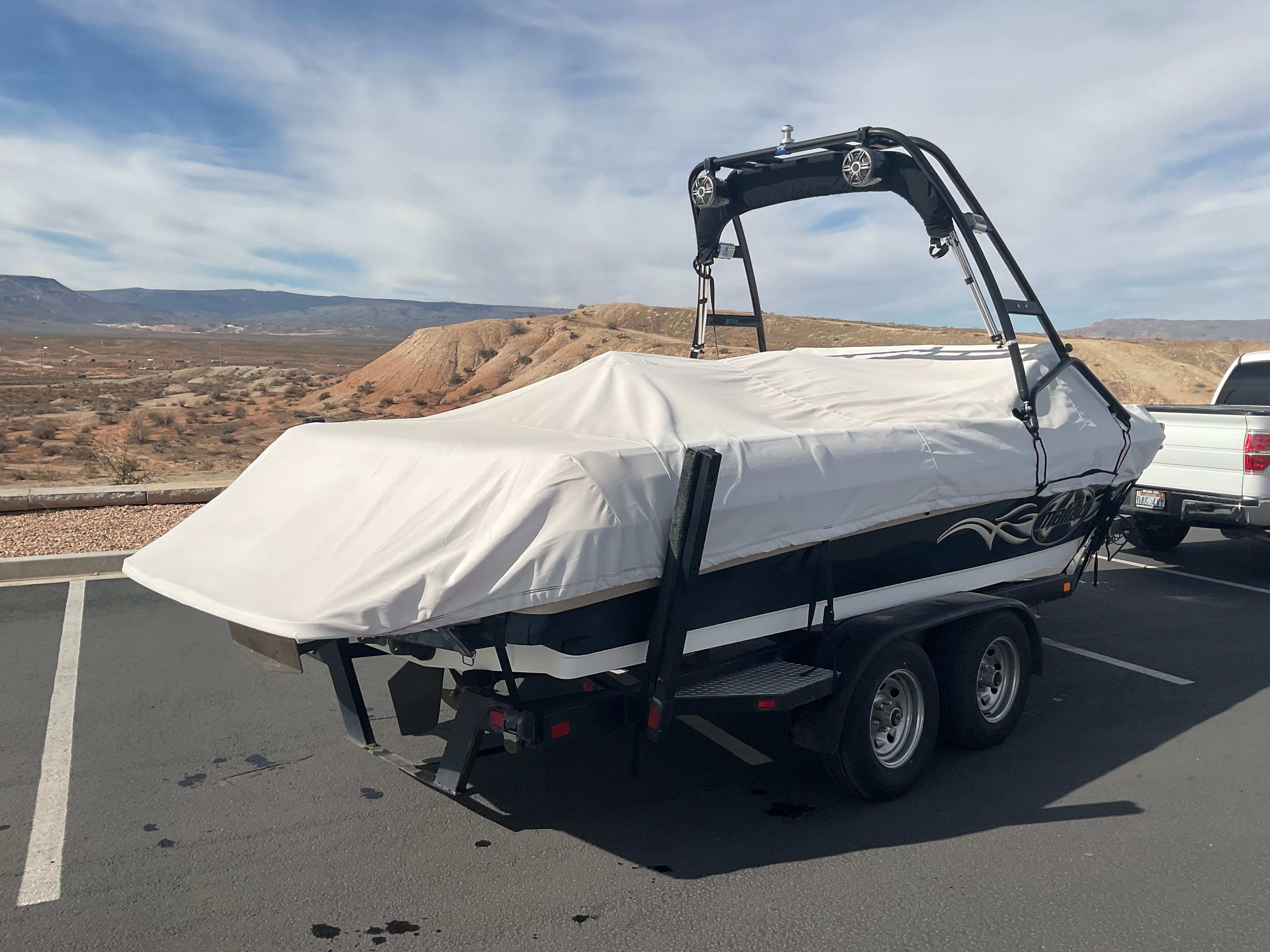 A 2003 Malibu Wakesetter 23 LSV on a trailer, covered, in a dry landscape.