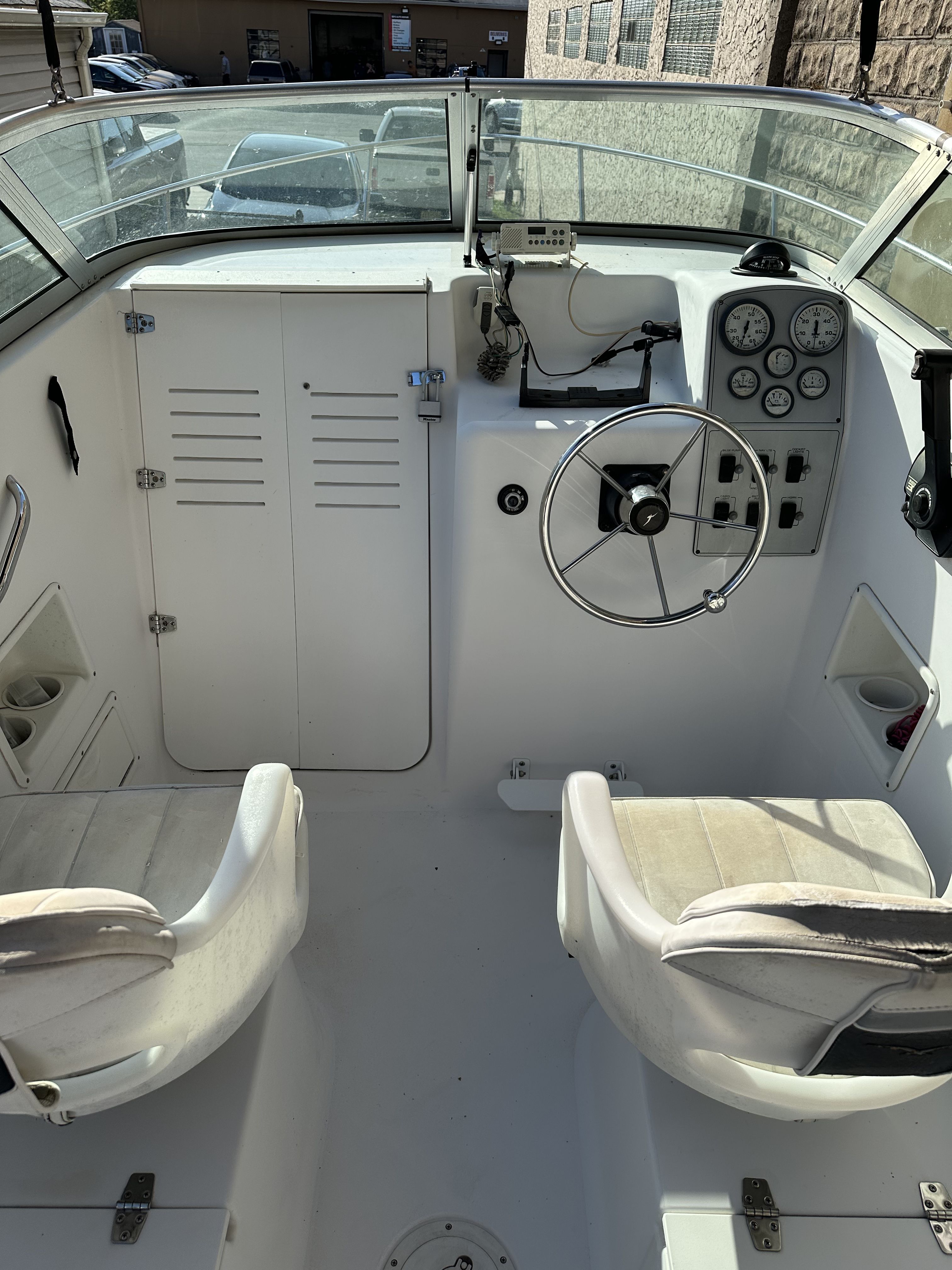 The image shows the cockpit of a 1999 Pro-Line 221 boat with two seats and a helm.