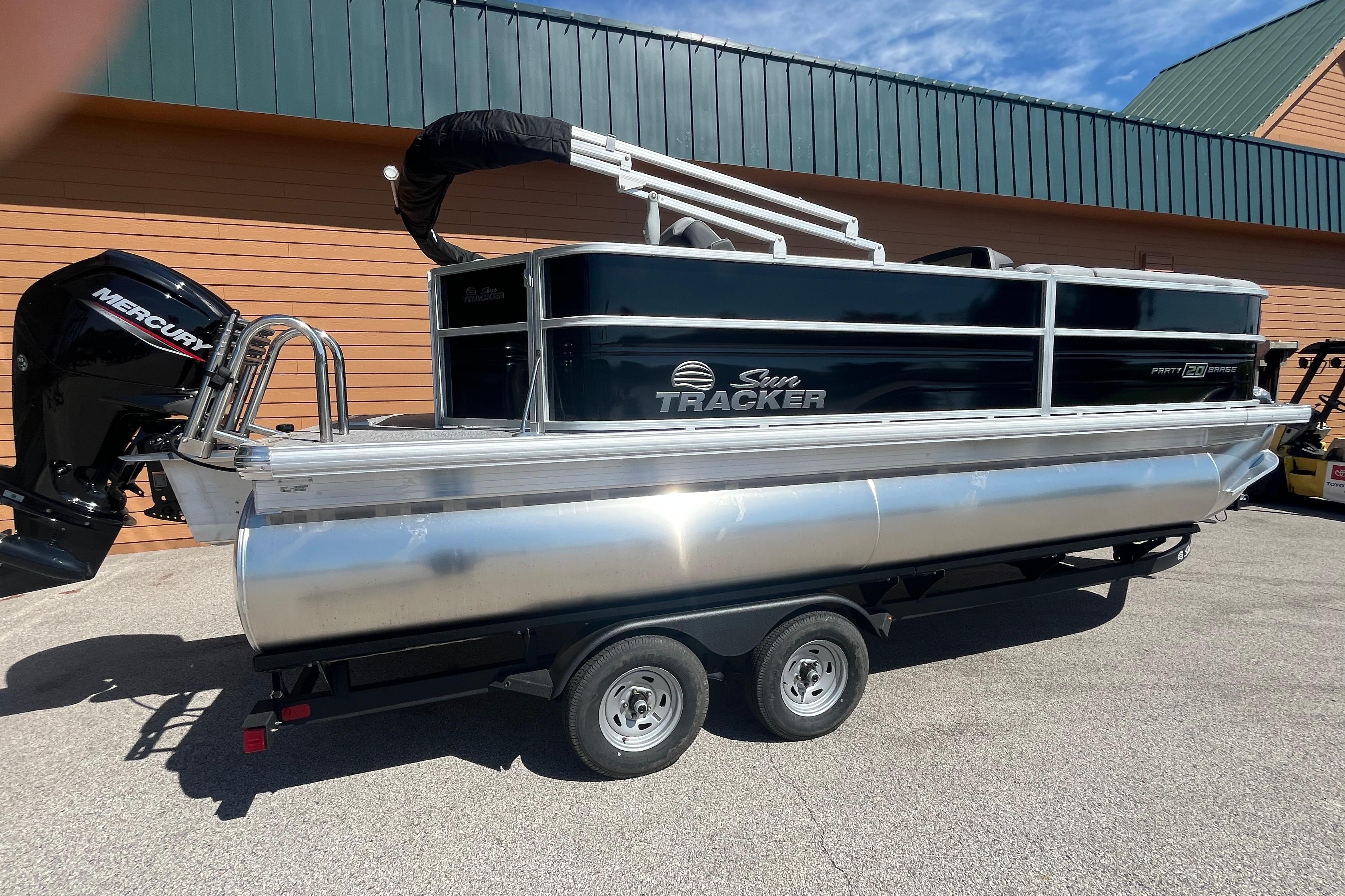 2026 Sun Tracker Party Barge 20 DLX pontoon boat on trailer, parked outdoors.