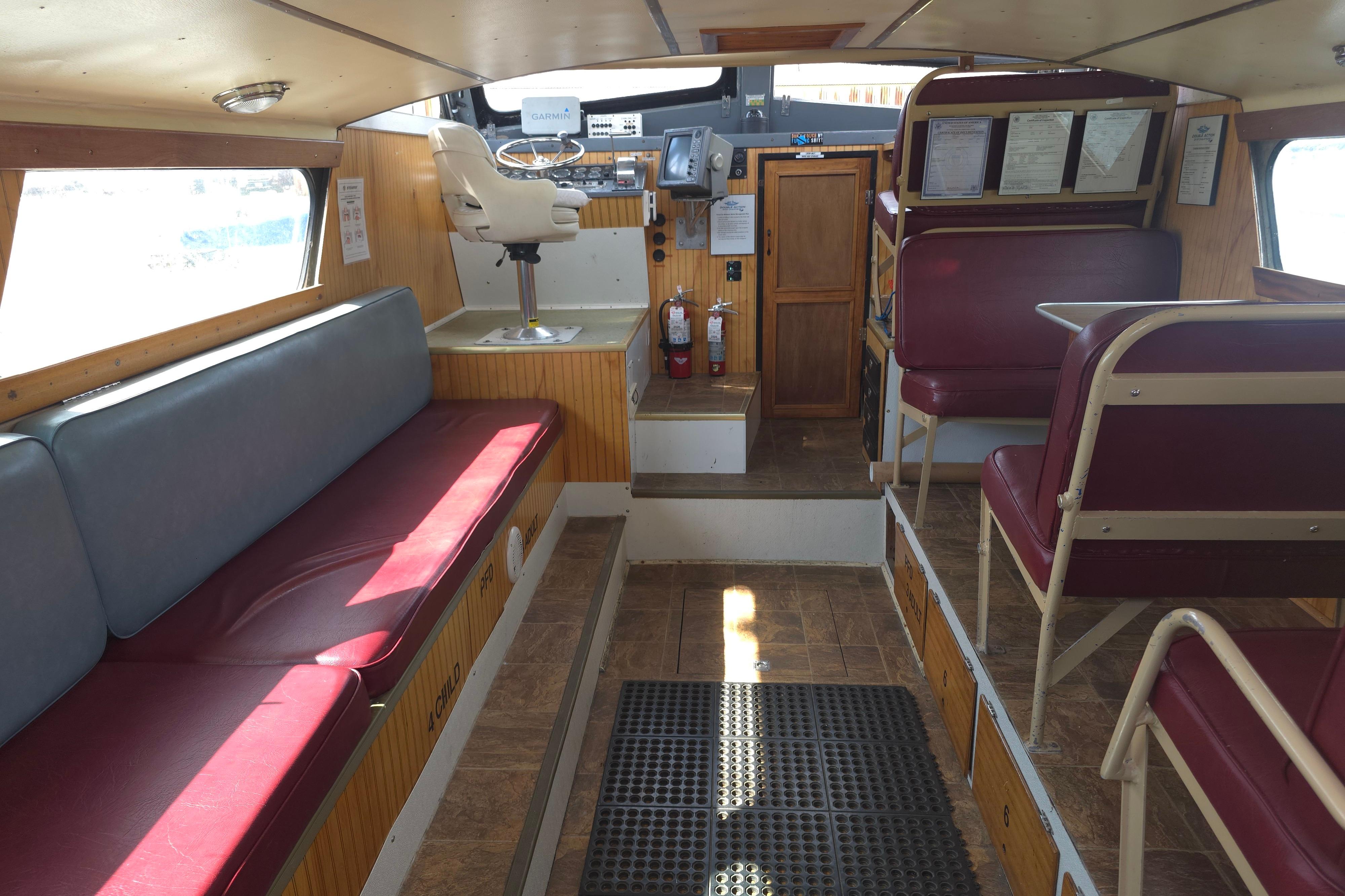 Interior of a 1974 Breaux's Bay Craft passenger boat, featuring seating and navigation area.