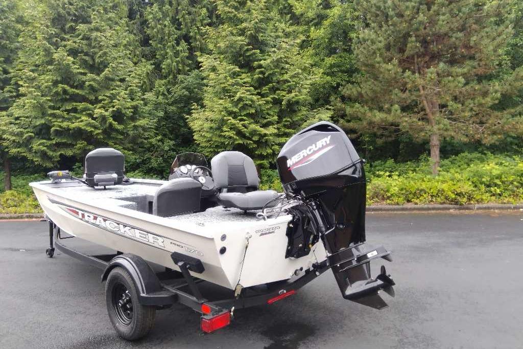2026 Tracker Pro 170 boat with Mercury engine, parked on a trailer near lush greenery.