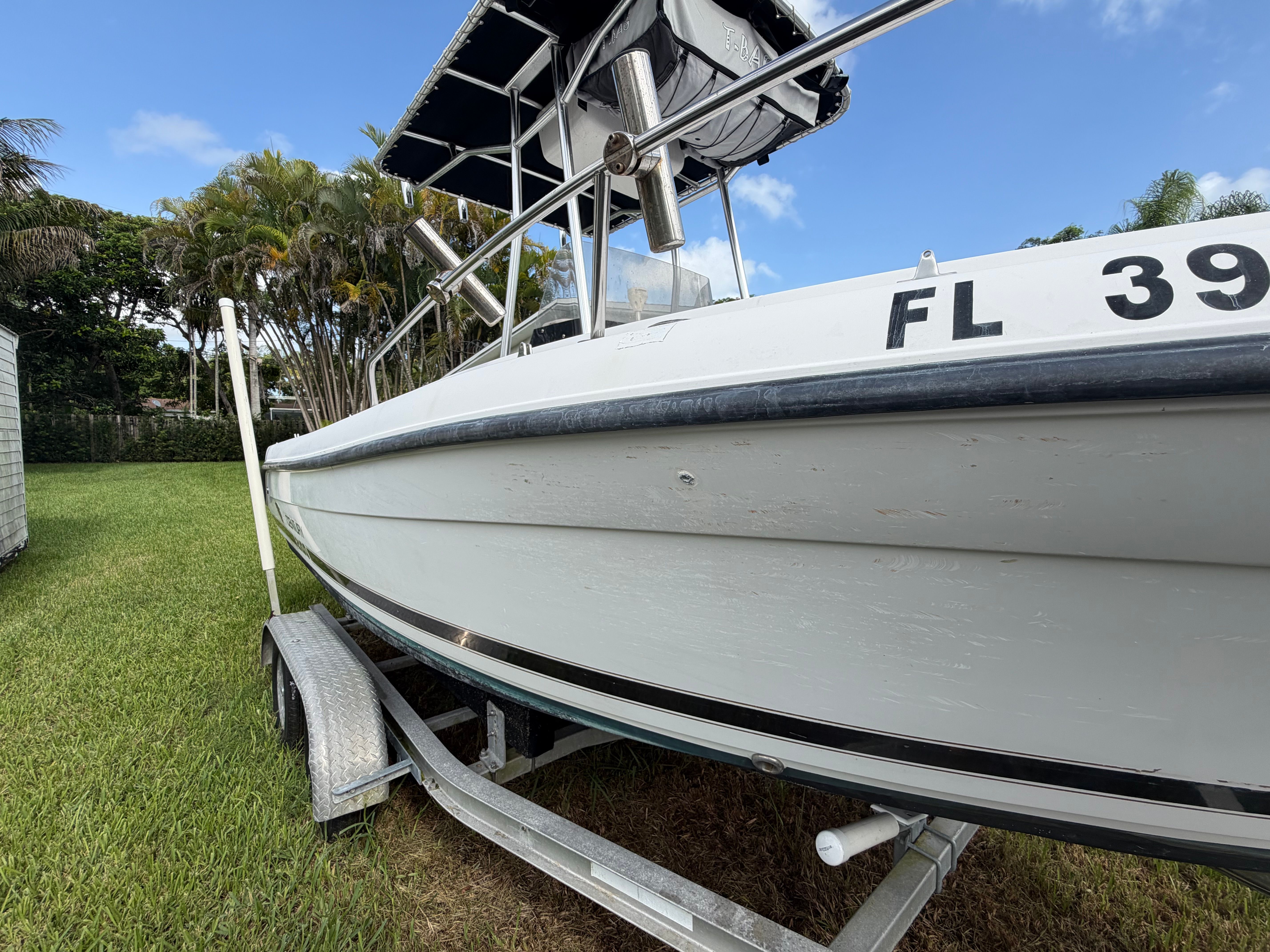 A 2001 Century 2100 Center Console boat on a trailer, parked on grass.