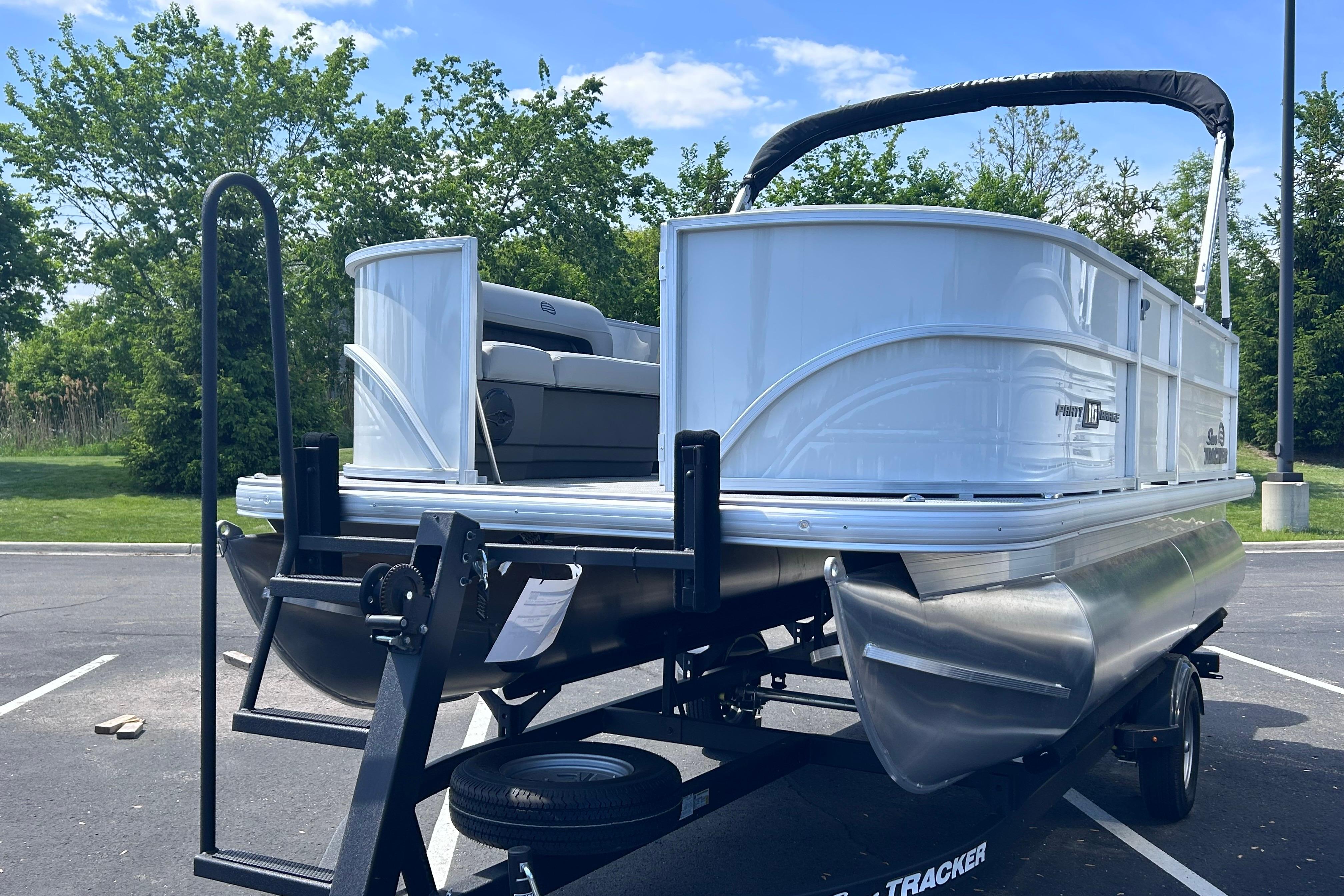 2026 Sun Tracker Party Barge 16 DLX pontoon boat on trailer in parking lot.