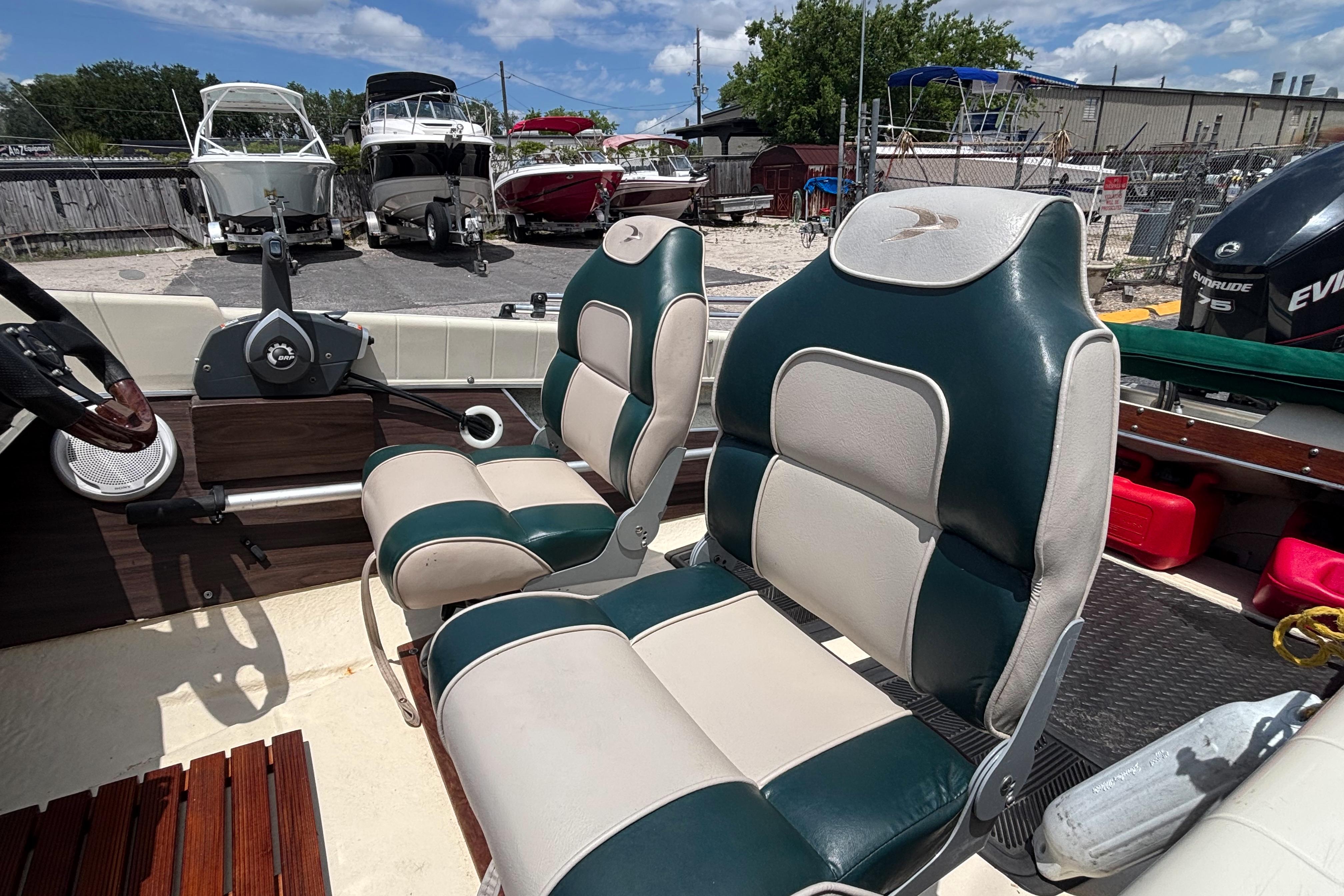 1966 Mohawk 15 boat interior with green and white seats, steering wheel, and docked boats in background.