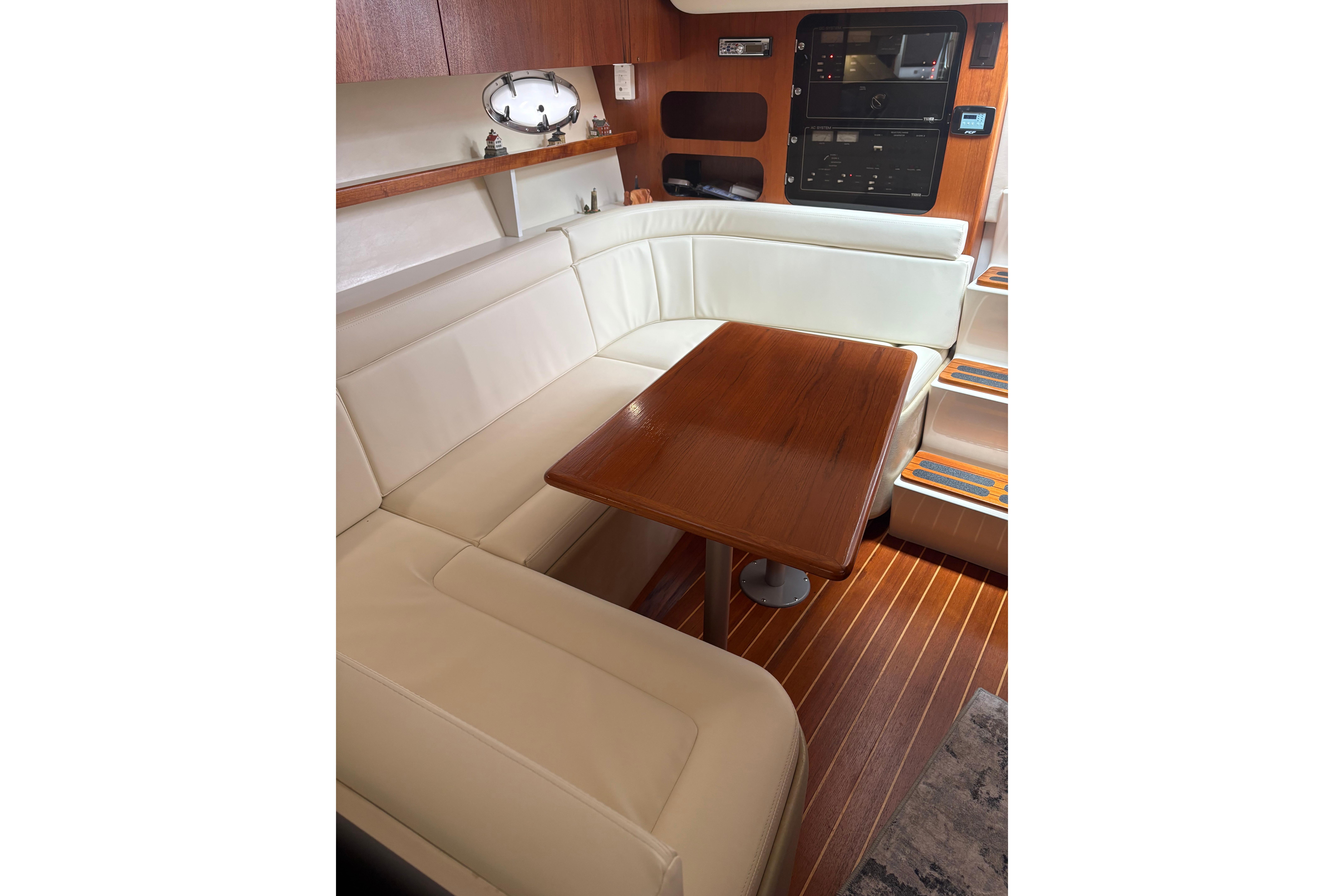 Interior of 1999 Tiara Yachts 3100 Open with white seating and wooden table.