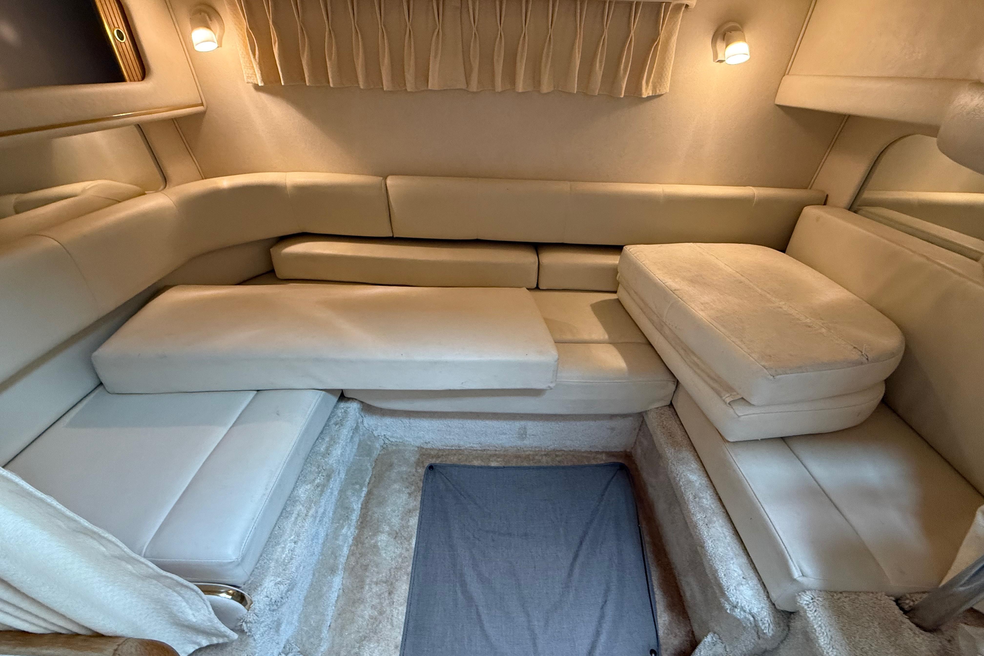1999 Sea Ray Sundancer 310 cabin interior with beige seating and soft lighting.