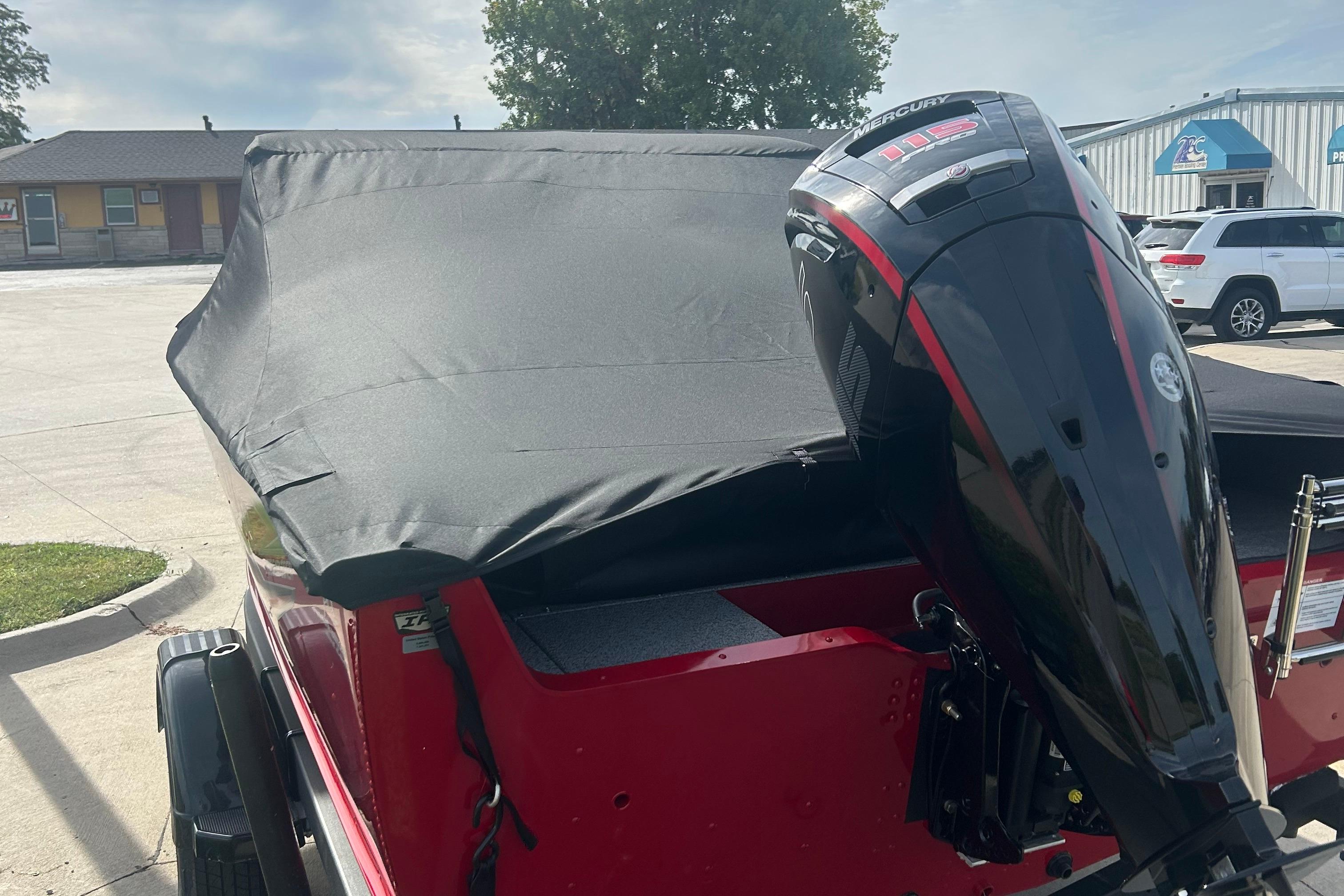 2026 Lund 1800 Explorer Sport boat with Mercury outboard motor, covered and parked outdoors.