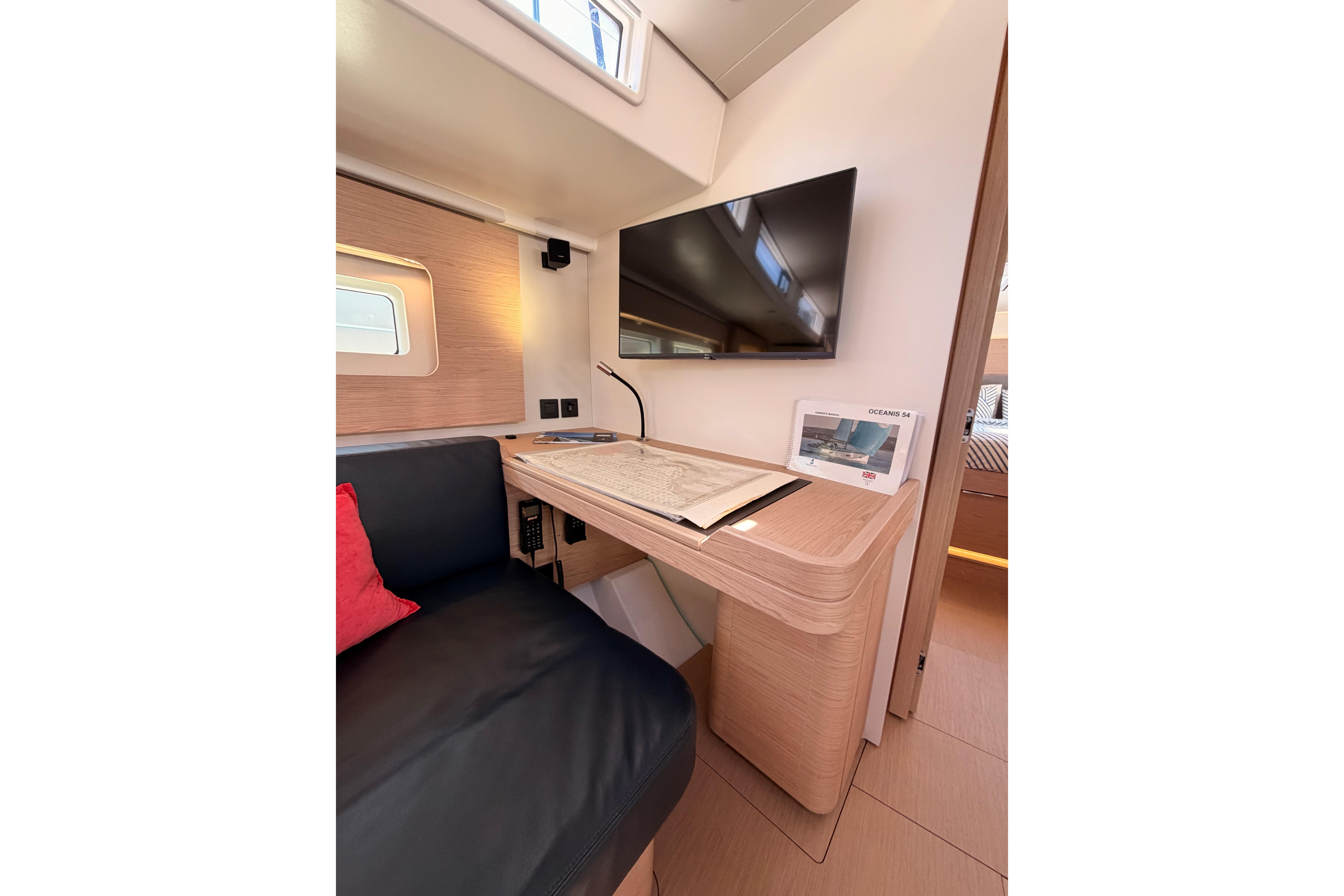 Interior of 2022 Beneteau Oceanis Yacht 54 with desk, TV, and seating area.