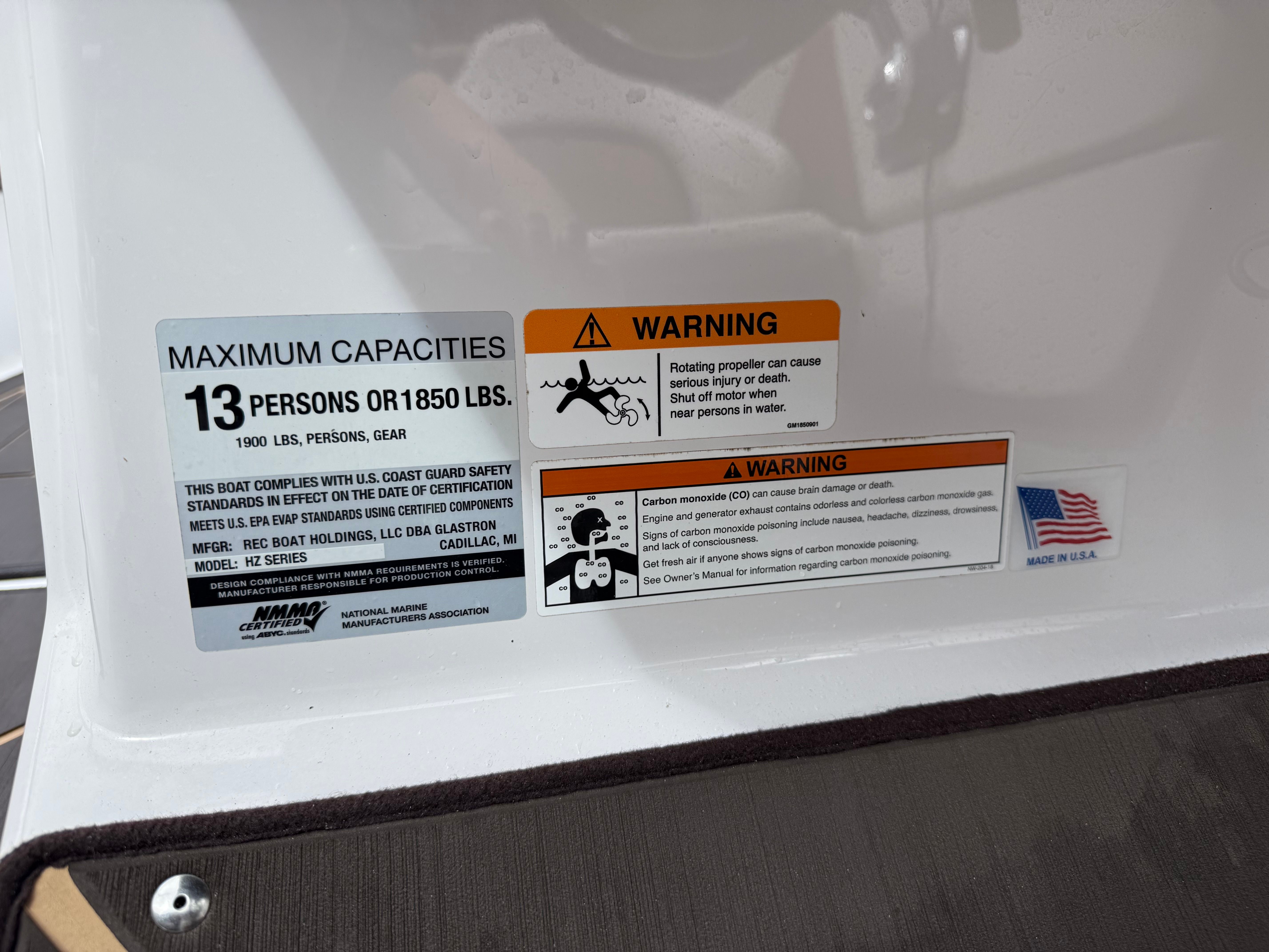 Warning labels and capacity information on a boat, including maximum persons and weight.