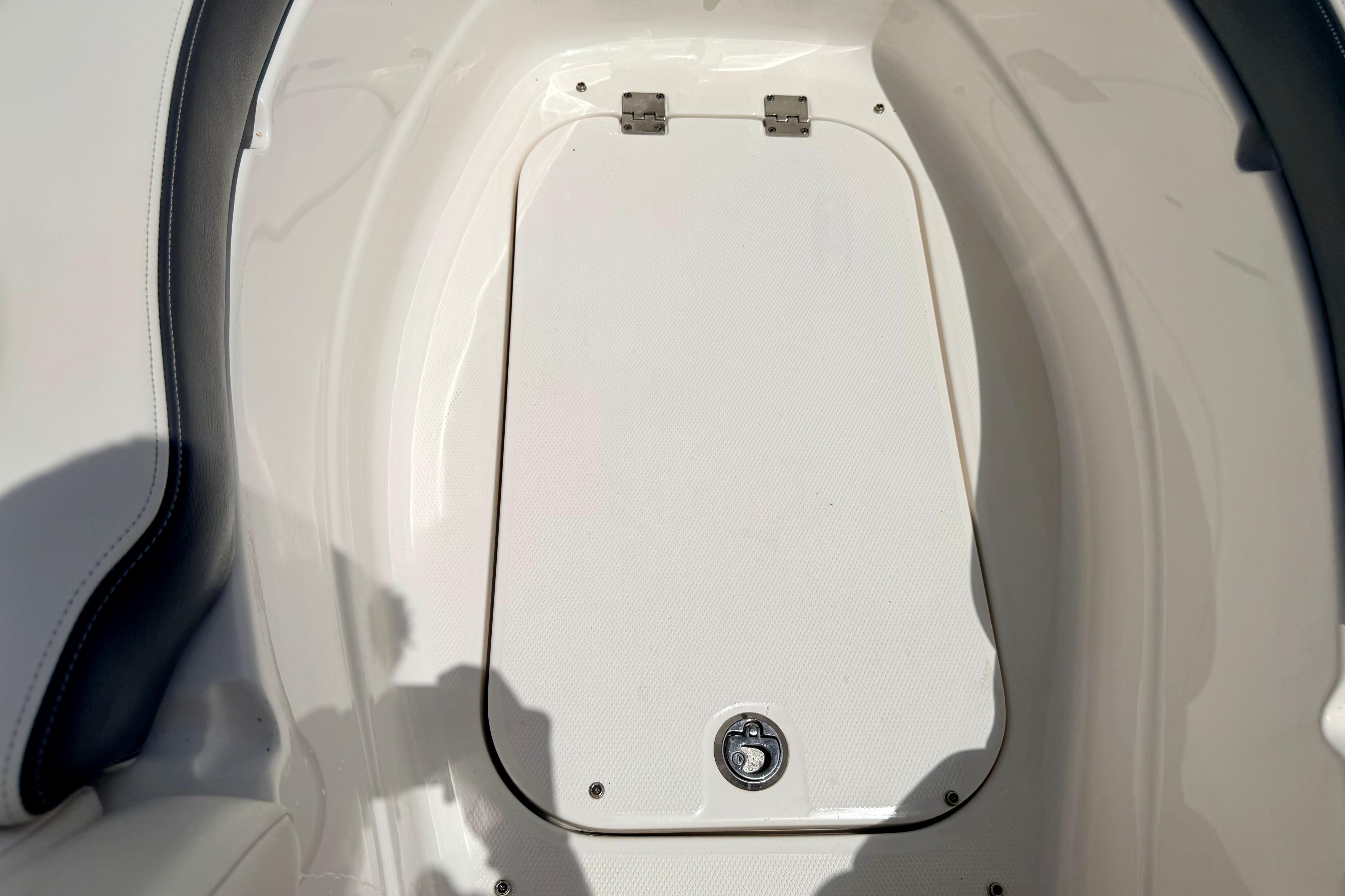 2015 Chaparral Sunesta 264 boat storage compartment with latch, white interior.