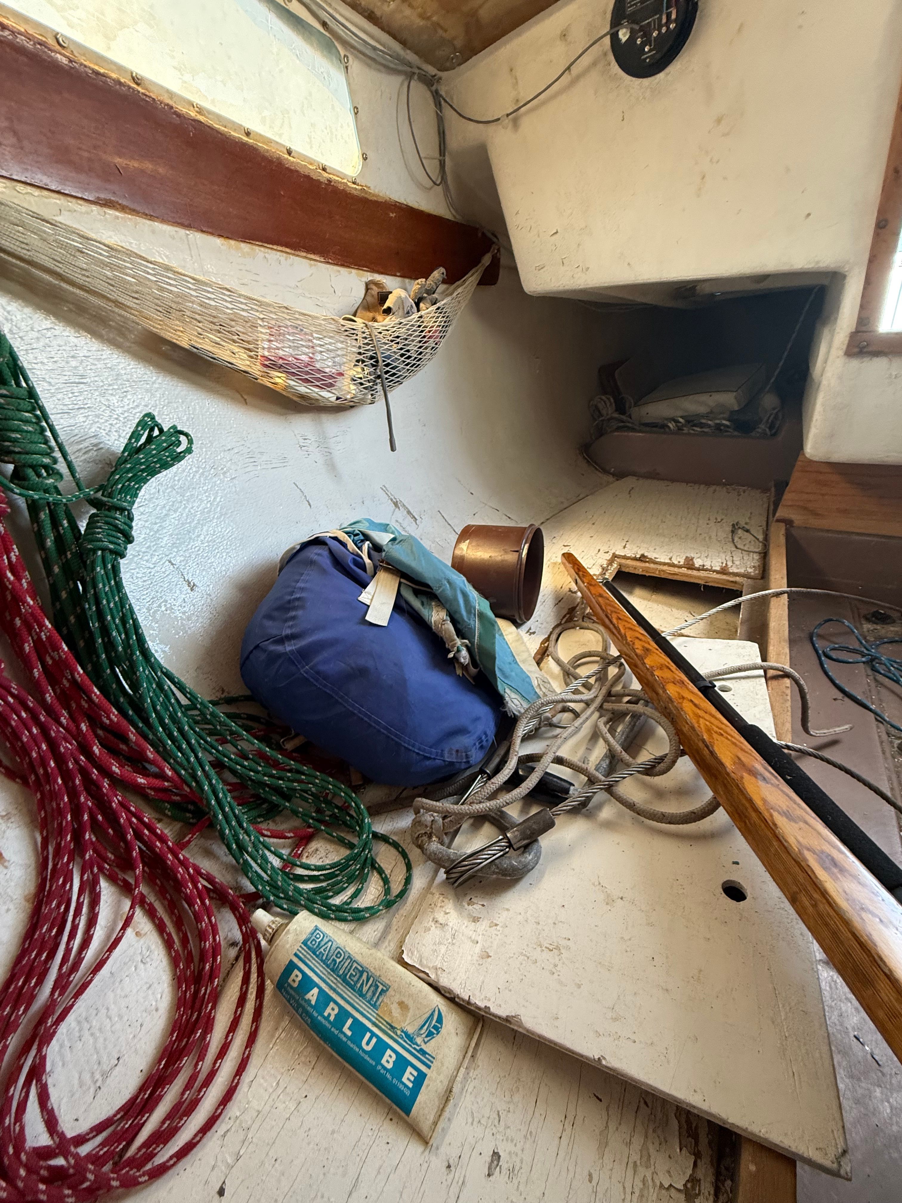The interior of a 1965 CAL 20 sailboat with ropes and equipment.